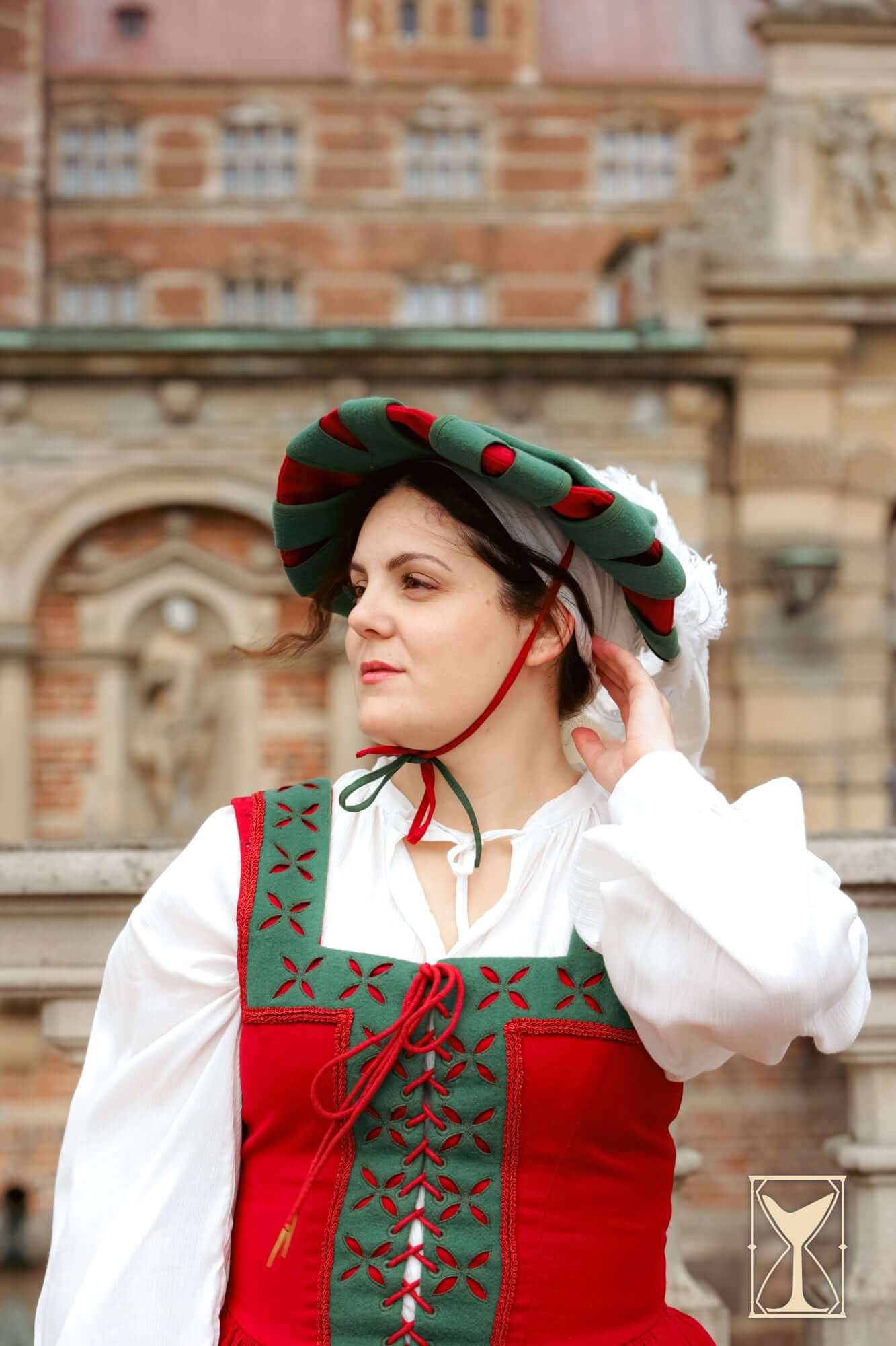 Woman wearing a traditional Landsknecht Hat with a layered design, set against a historic background.