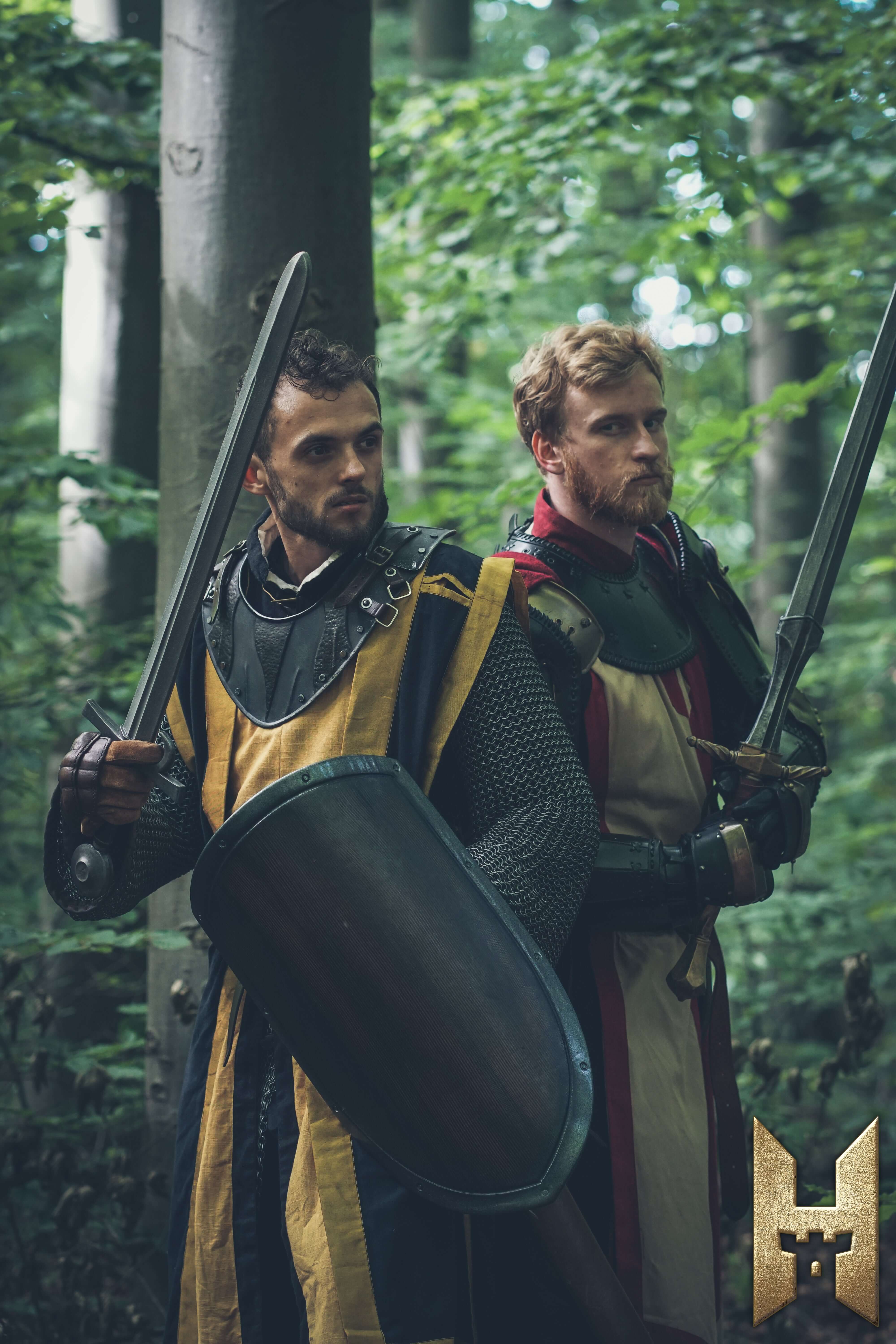 Two medieval fighters in armor holding swords and a shield in a forest setting, featuring the Milanese Sword.