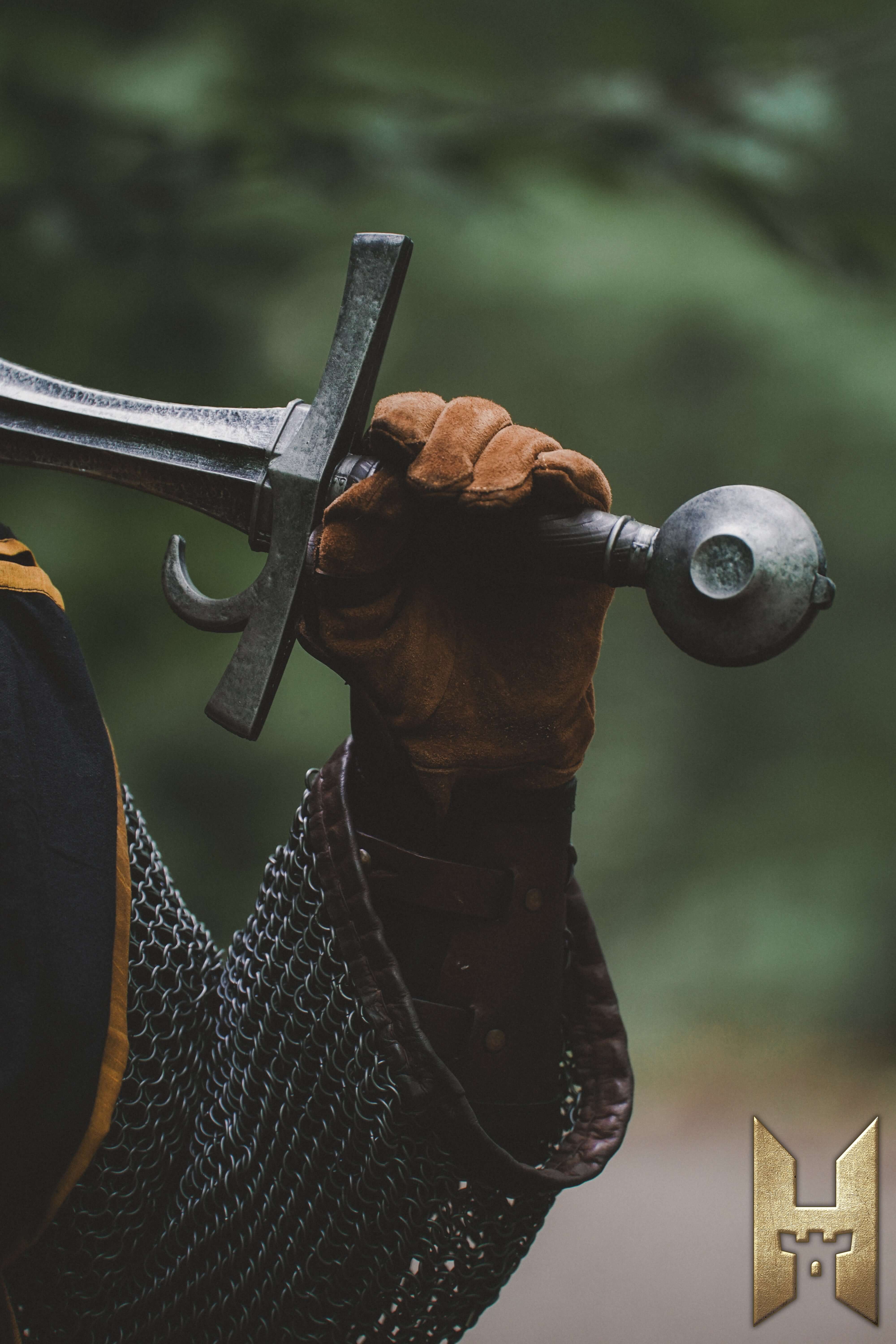 A warrior holding a Milanese Sword with a gloved hand, showcasing its sleek design and durability.