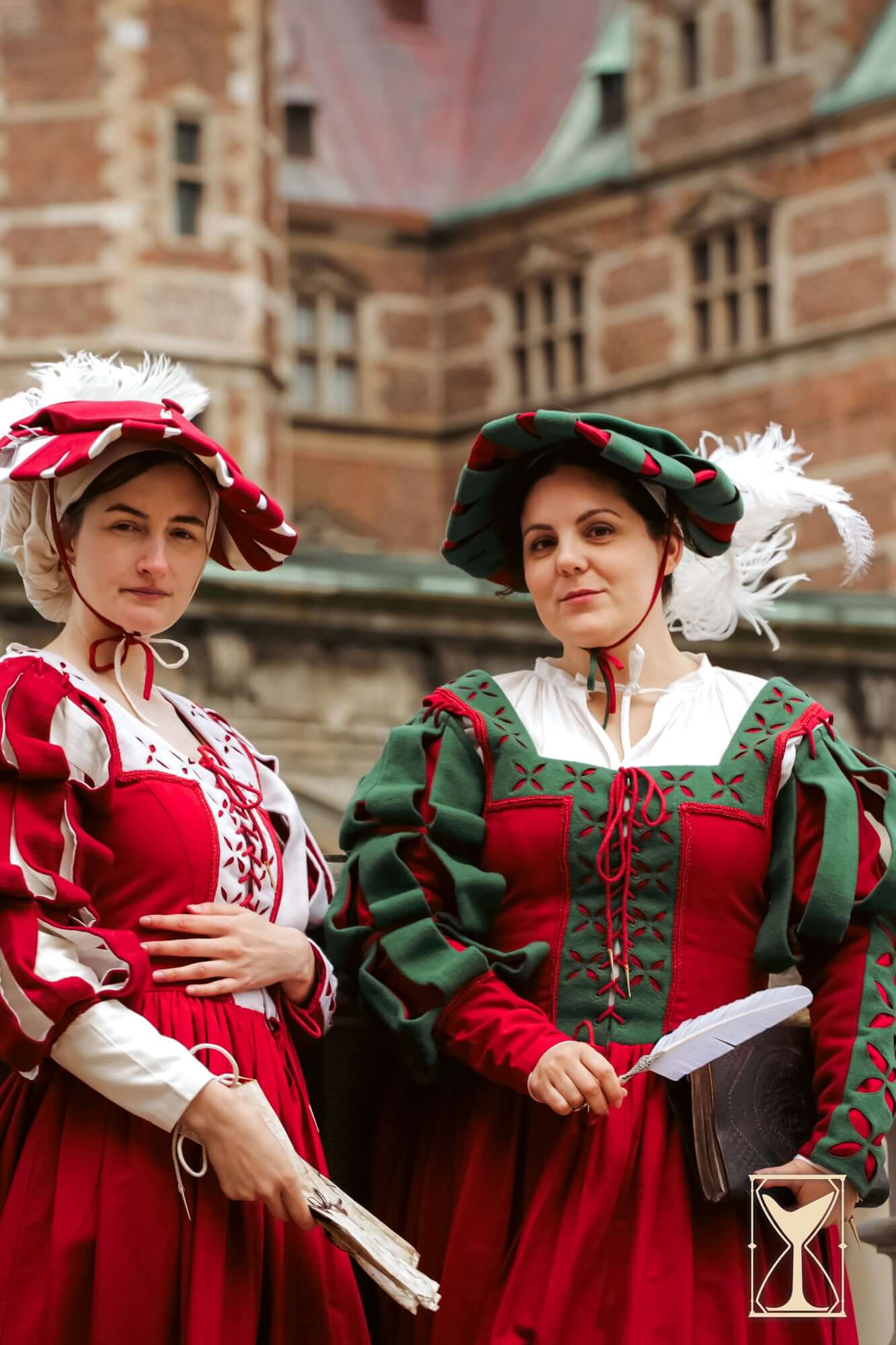 Two women dressed in Kampfrau dresses featuring bold red and green colors with historical flair.