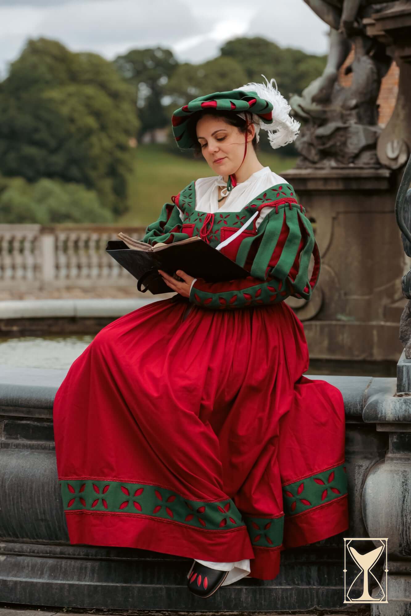 Woman wearing a Kampfrau dress with bold red and green colors, showcasing historical flair while reading.