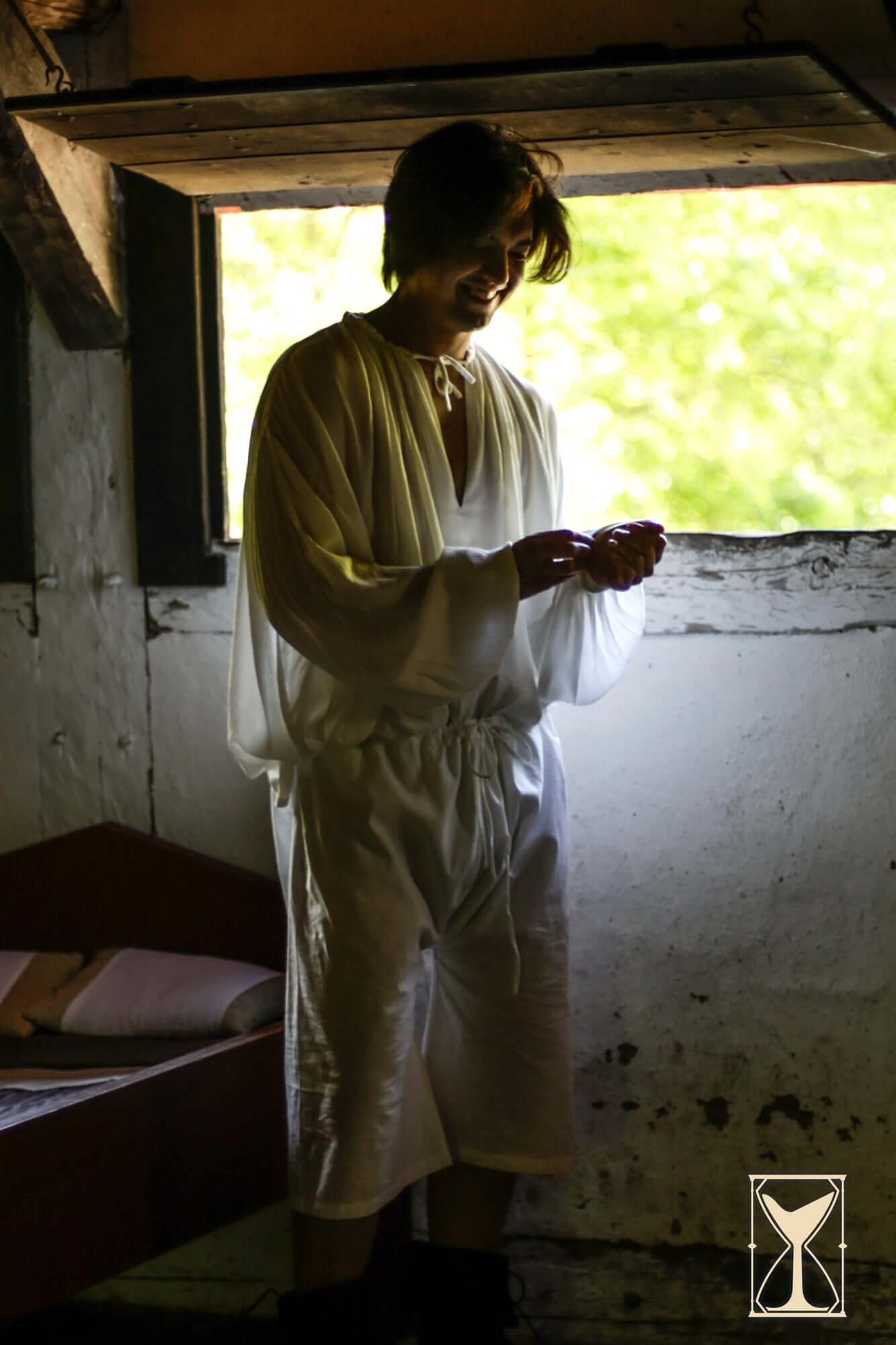 A person wearing Braies - Long standing by a window, showcasing medieval-themed attire.