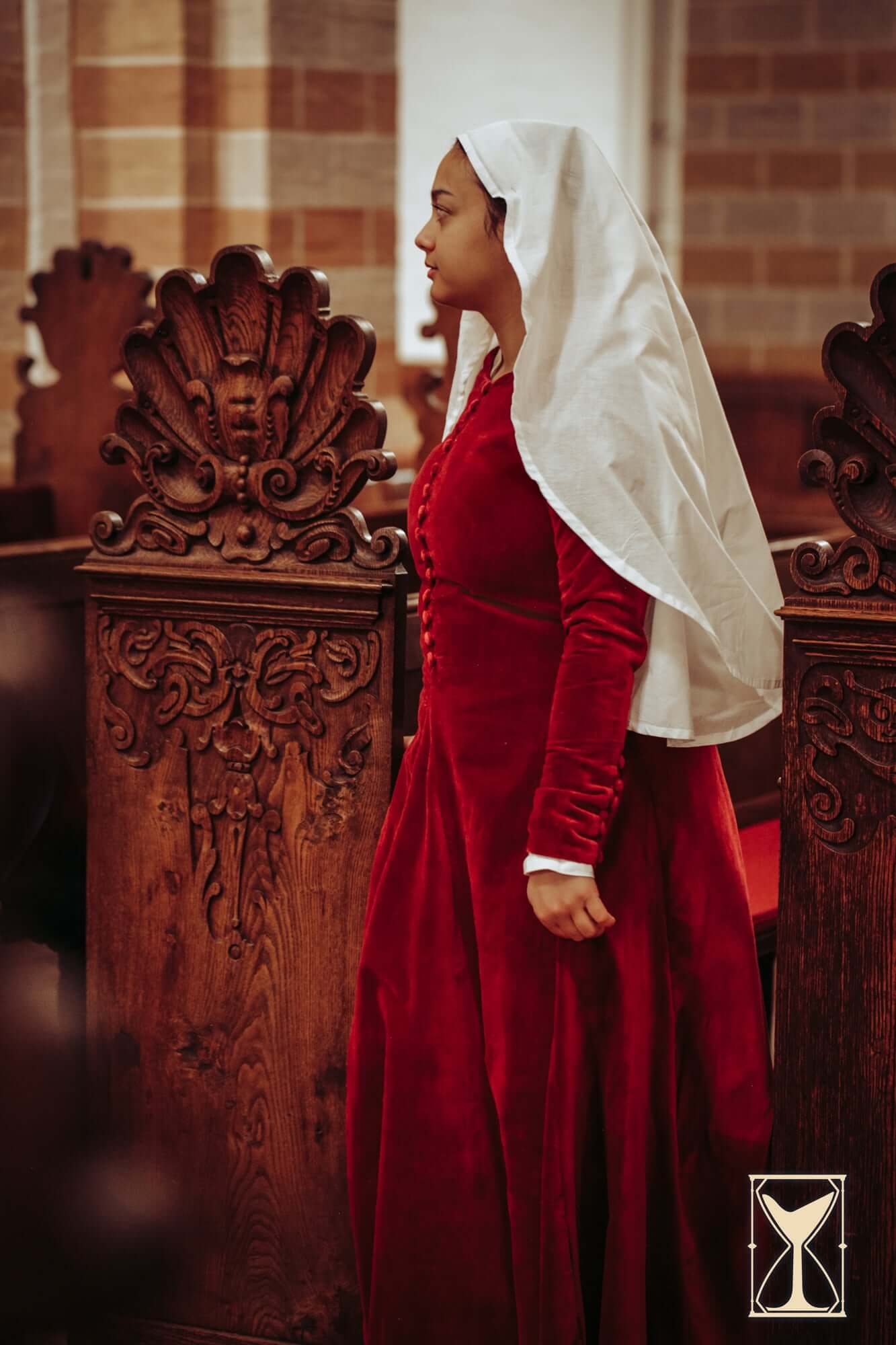 Cotehardie Colette worn by a woman in a historic setting, showcasing its rich velvet fabric and period design.