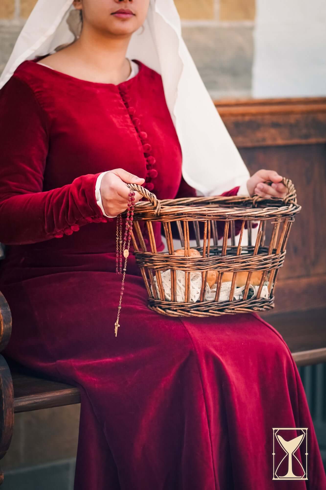 Cotehardie Colette velvet dress in rich red worn by woman holding a basket.