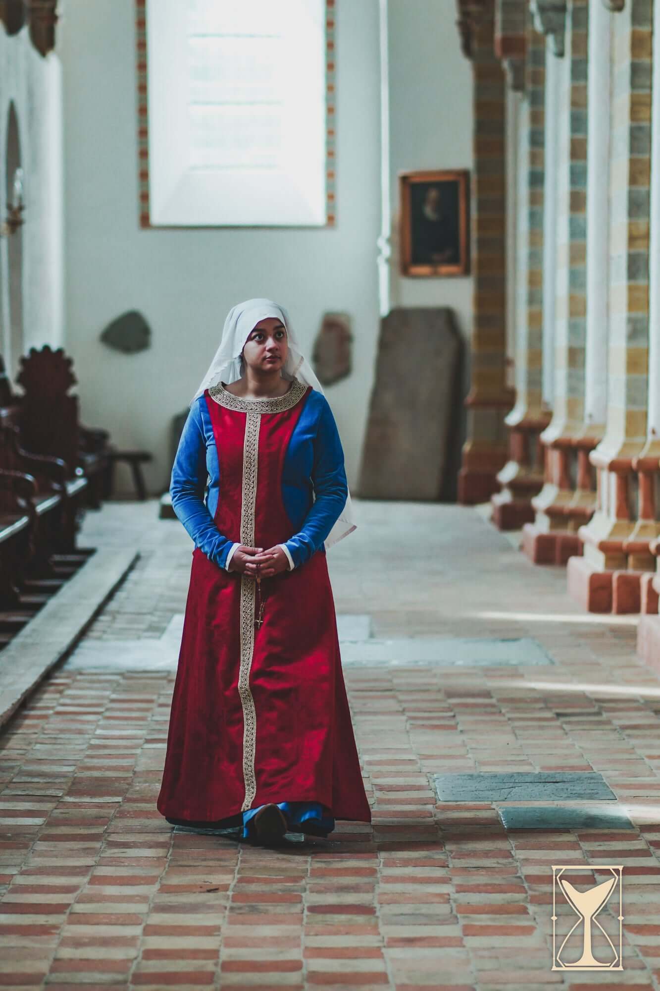 Pellote - Medieval Dress worn by a model in a historical setting, showcasing its vibrant colors and design.