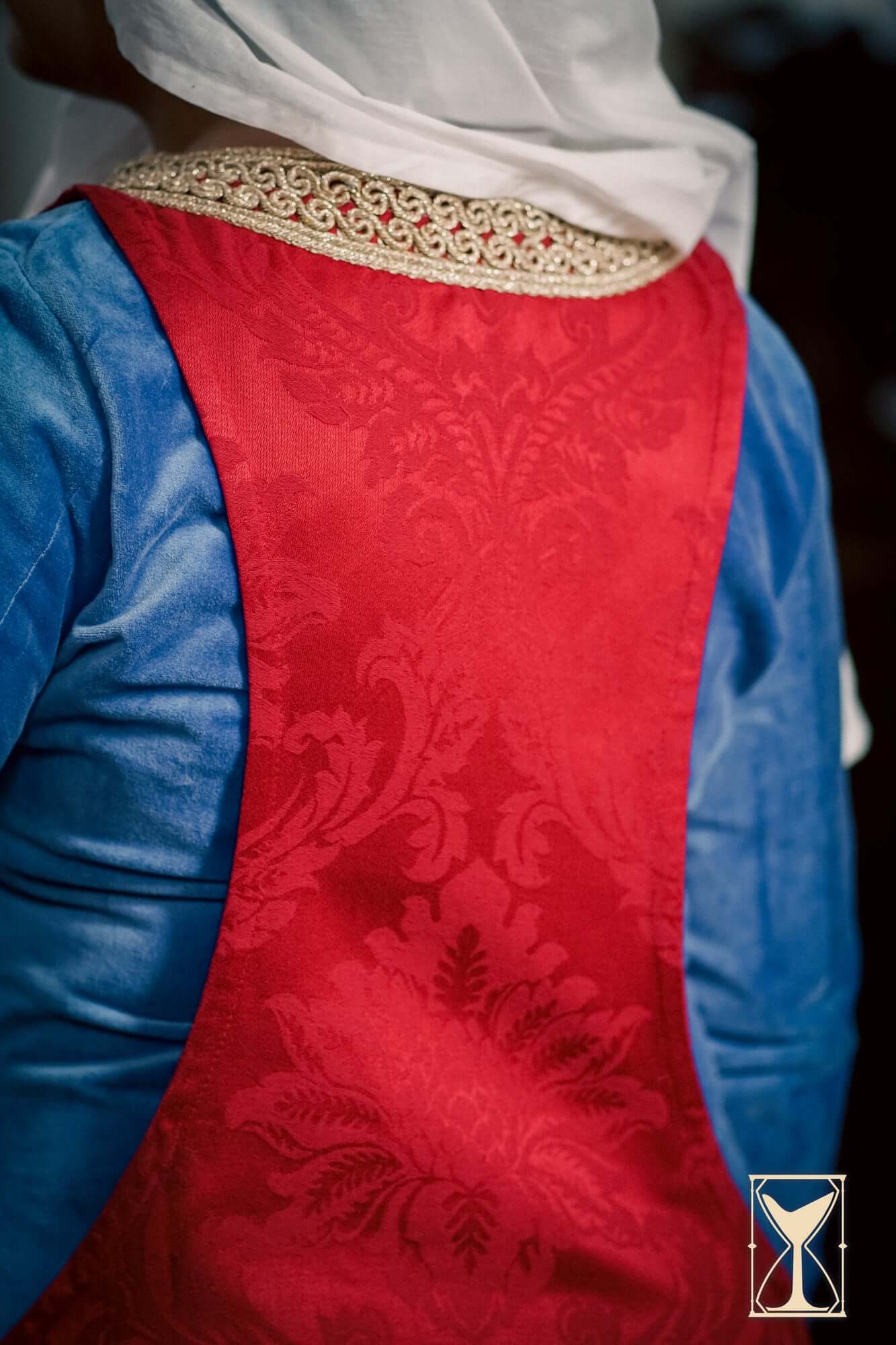 Pellote - Medieval Dress showcasing the intricate red fabric and elegant collar detail of this historical surcoat.