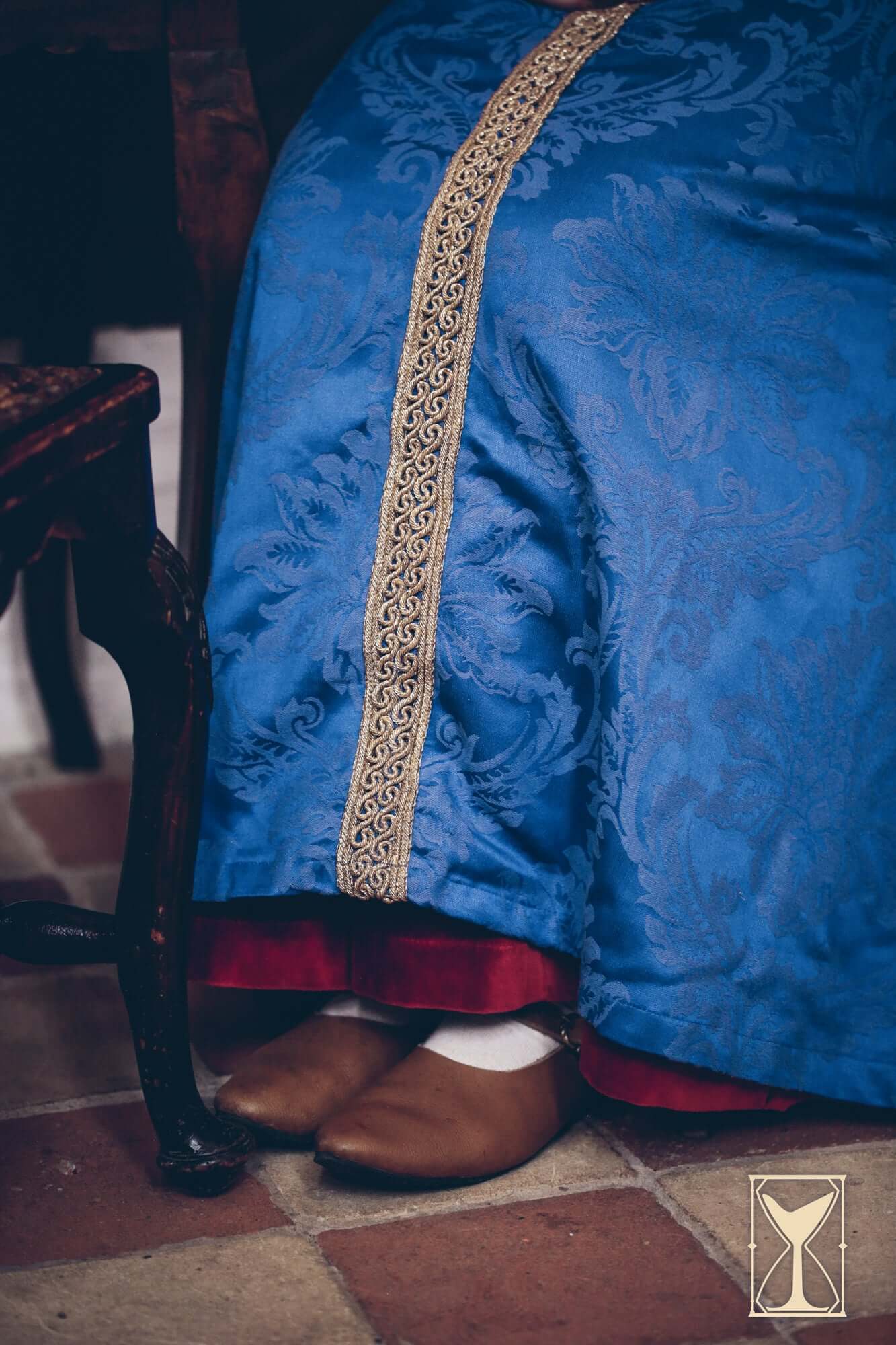 Pellote - Medieval Dress featuring blue brocade fabric with gold trim and brown shoes, styled for a medieval look.