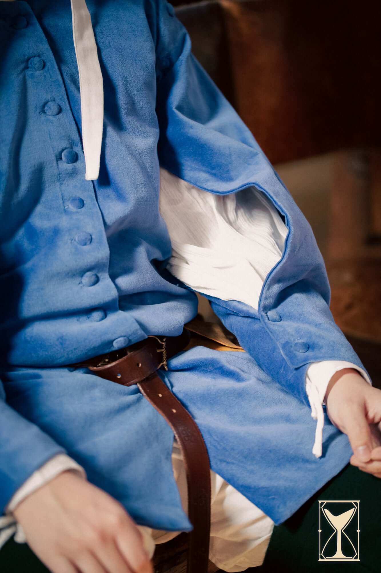 Model wearing a blue Velvet Surcoat with a white shirt underneath, showcasing medieval fashion details.