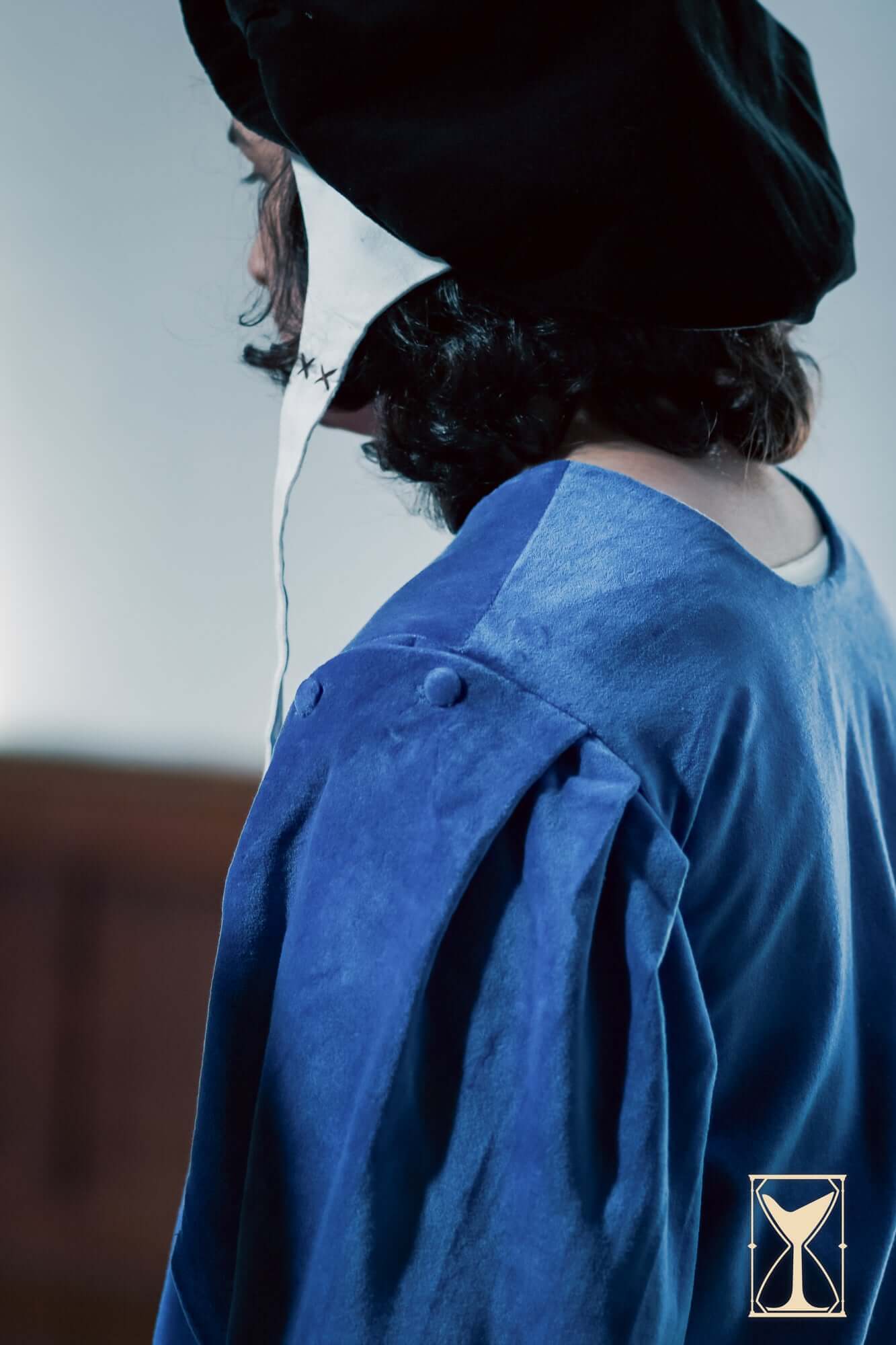 Back view of a person wearing a Velvet Surcoat, showcasing its rich blue fabric and distinctive sleeve design.