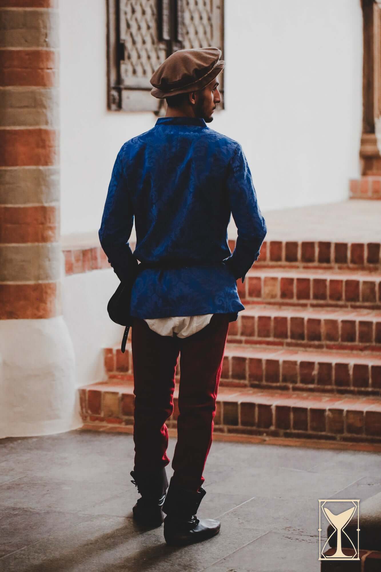 A man wearing a Flat Hat Edward and a blue shirt, showcasing a Renaissance-inspired look.