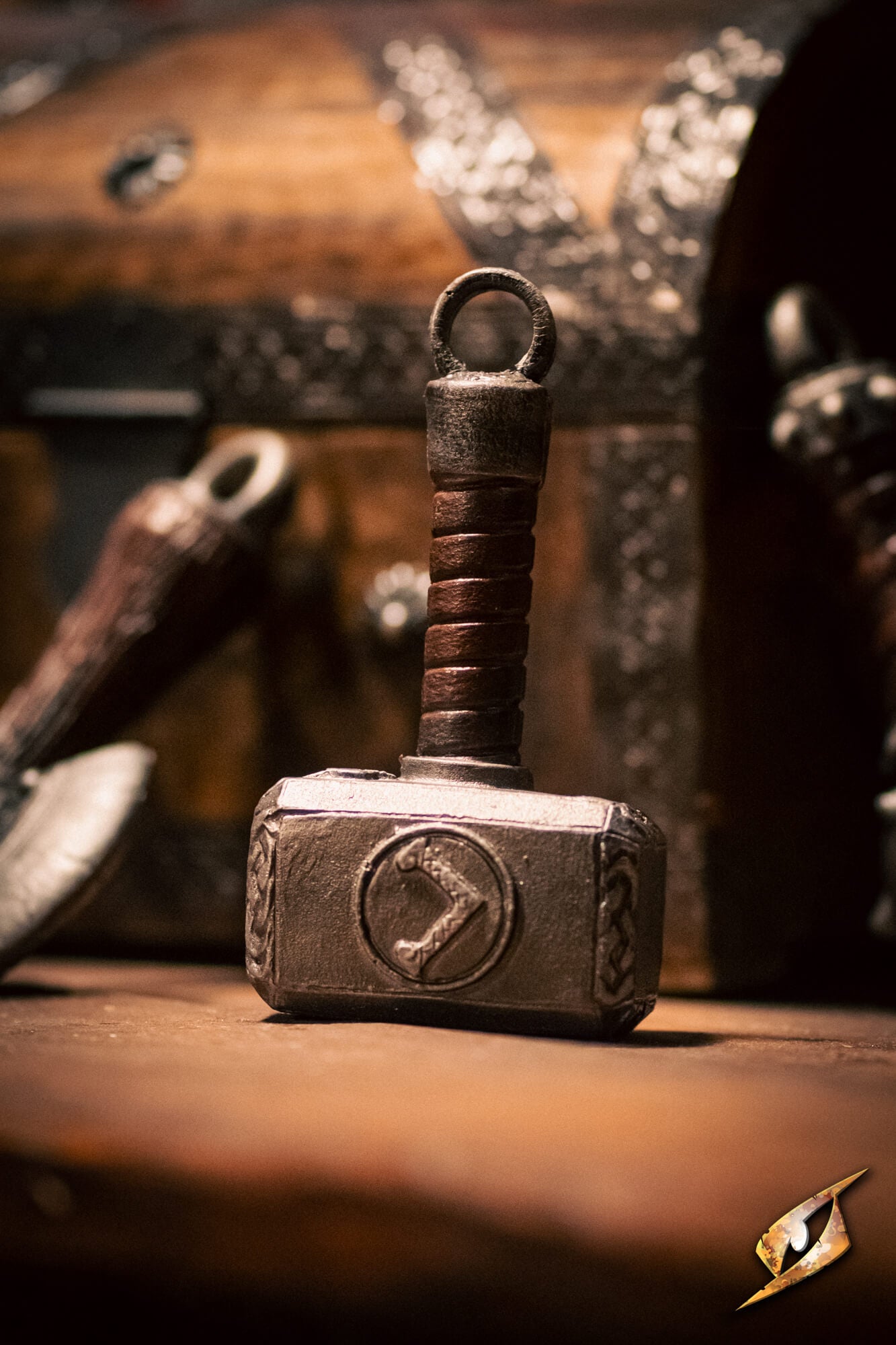 A miniature replica of Thor's hammer, Mjolnir, standing upright on a wooden surface with a dark, atmospheric background.