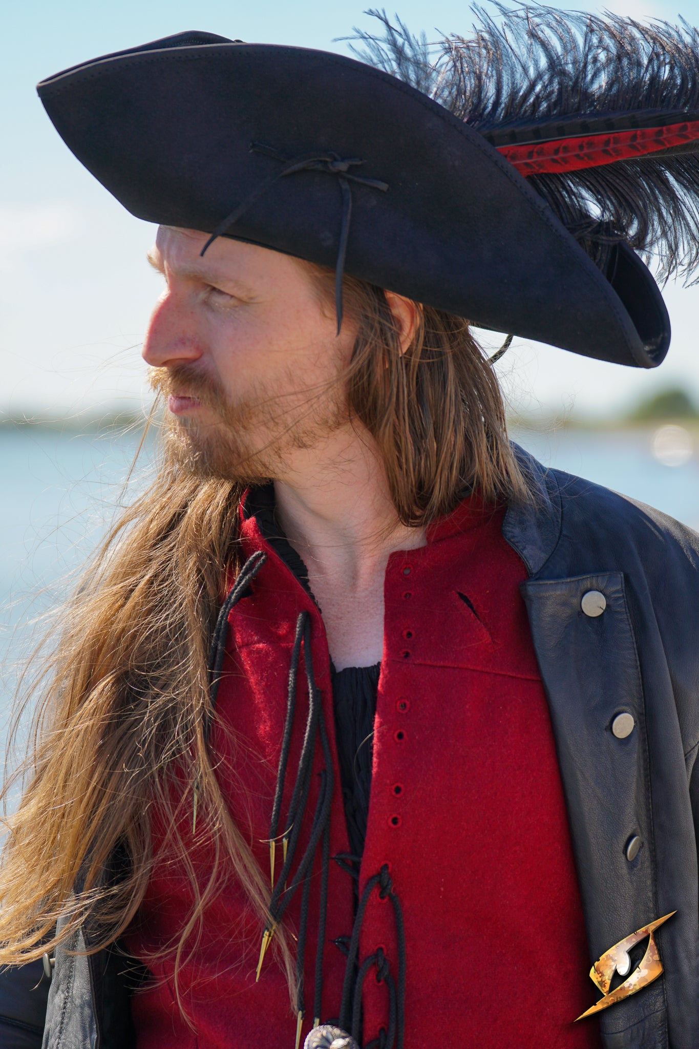 Man wearing a Simple Leather Pirate Tricorn Hat with a feather, dressed in a pirate costume by the water.