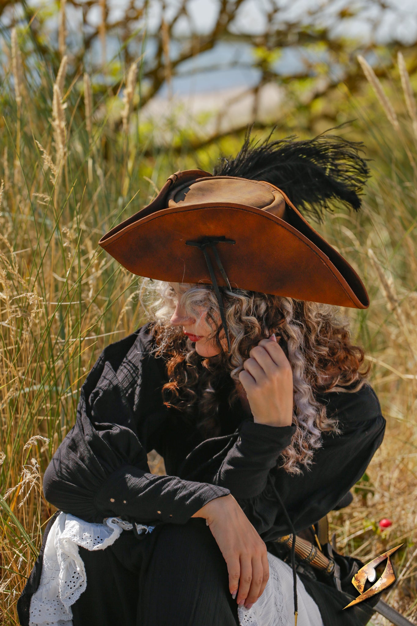 Woman outdoors wearing a Simple Leather Pirate Tricorn Hat with a feather, surrounded by tall grass.