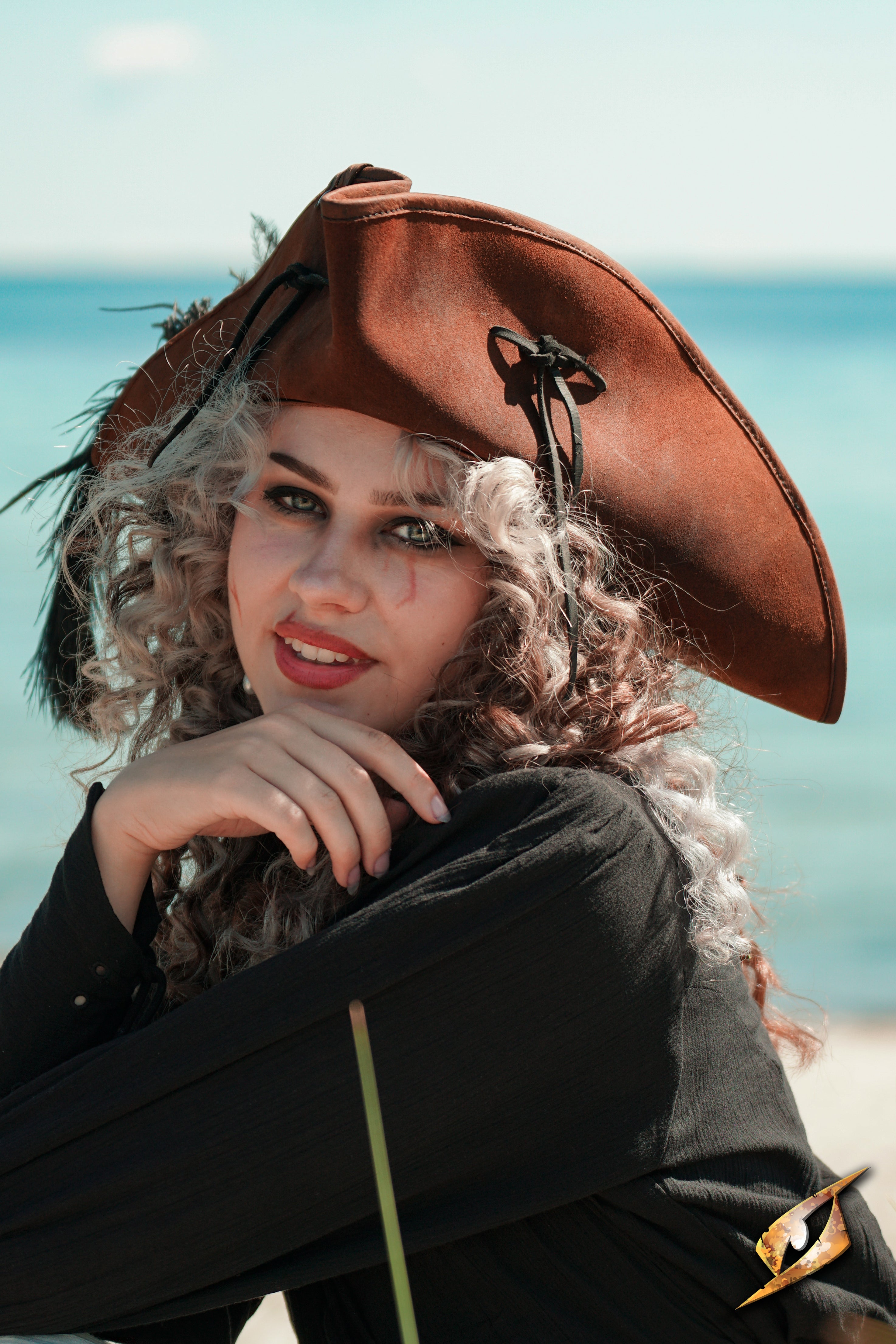 A model wearing a Simple Leather Pirate Tricorn Hat by the sea, showcasing its distinctive three-cornered design.