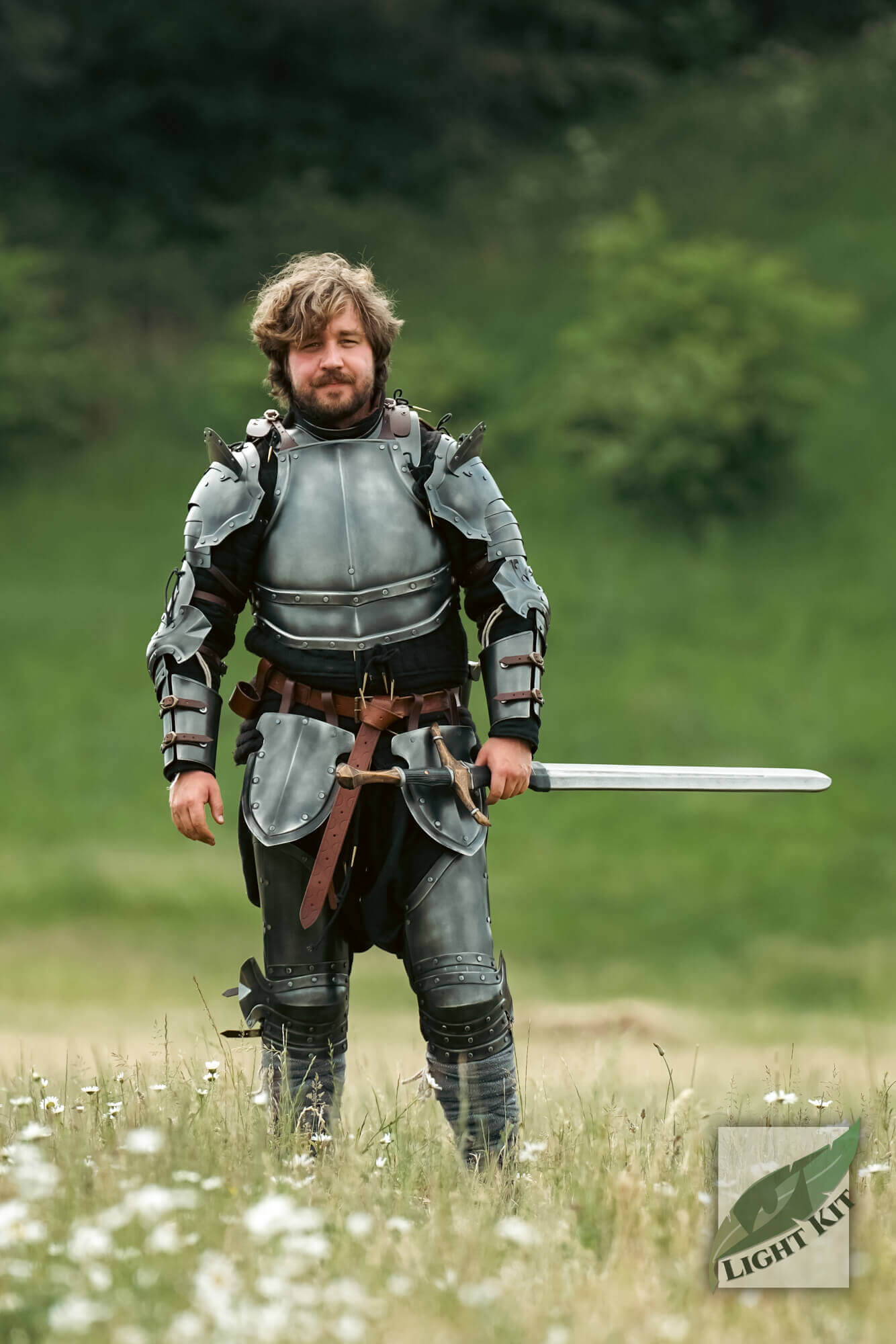 Man wearing Captain Complete Set - Light Kit armor with sword in a field, showcasing the polished design and style.
