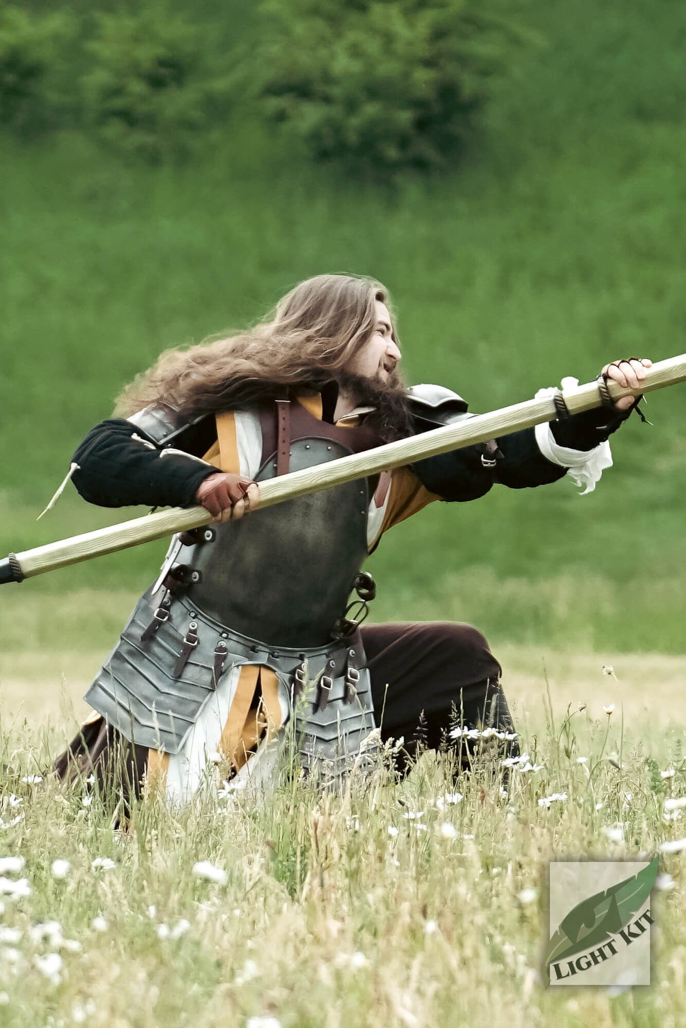 A warrior in the Merc Armour Set - Light Kit, wielding a spear in a grassy field, showcasing mobility and rugged design.