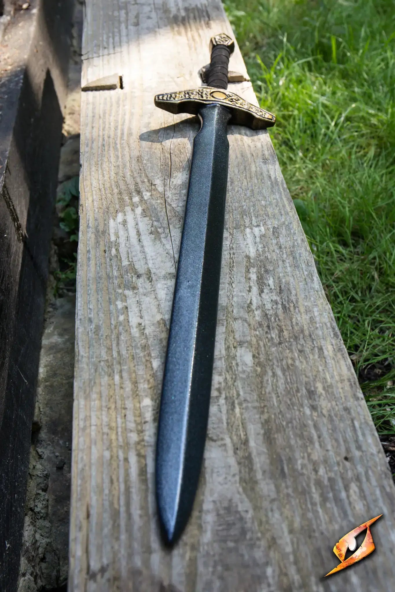Adventure - 85 cm sword resting on a wooden bench outdoors, showcasing its sleek design and intricate details.