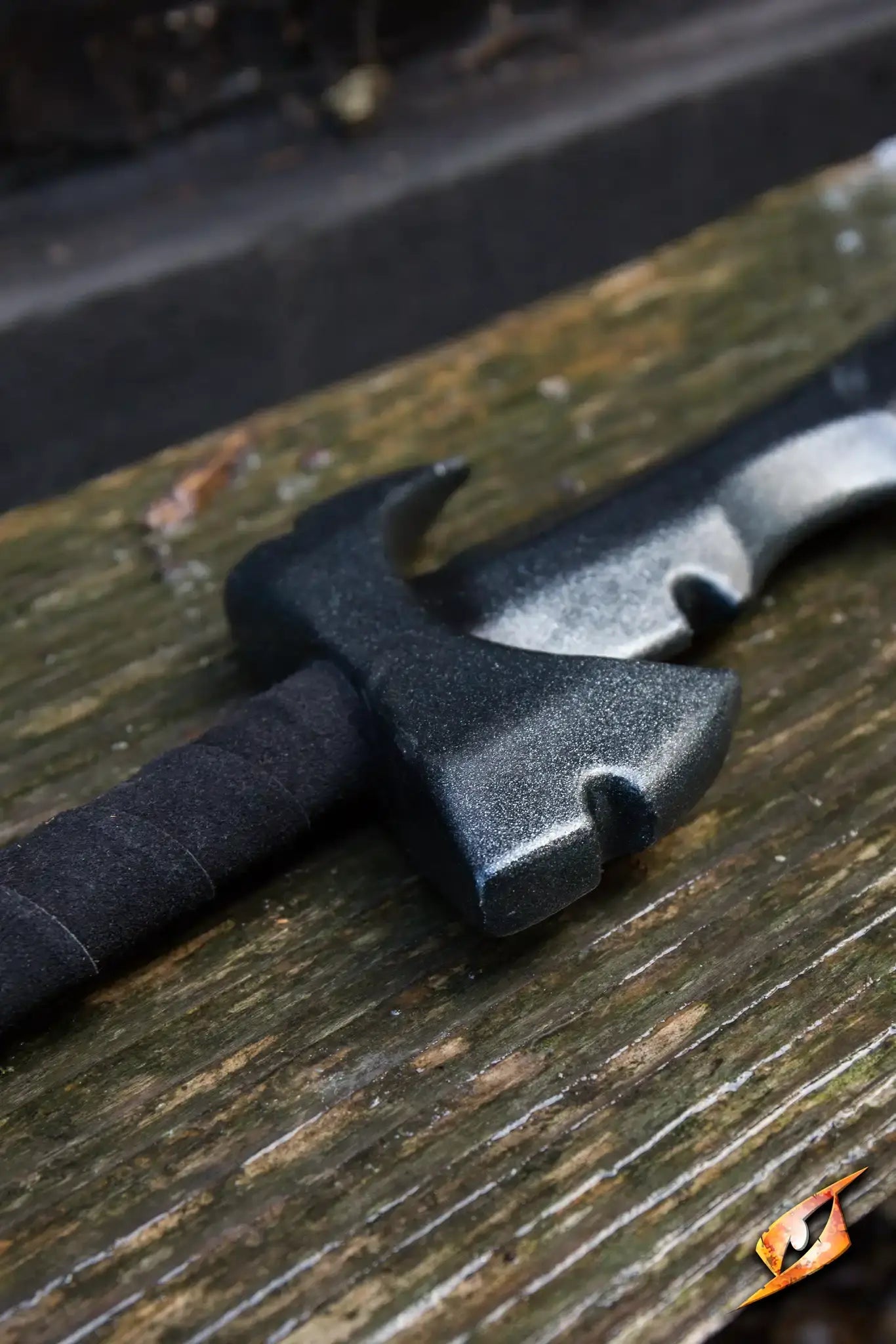 Close-up of the Assassin - 85 cm sword, showcasing its dark blade and wrapped handle, resting on weathered wood.