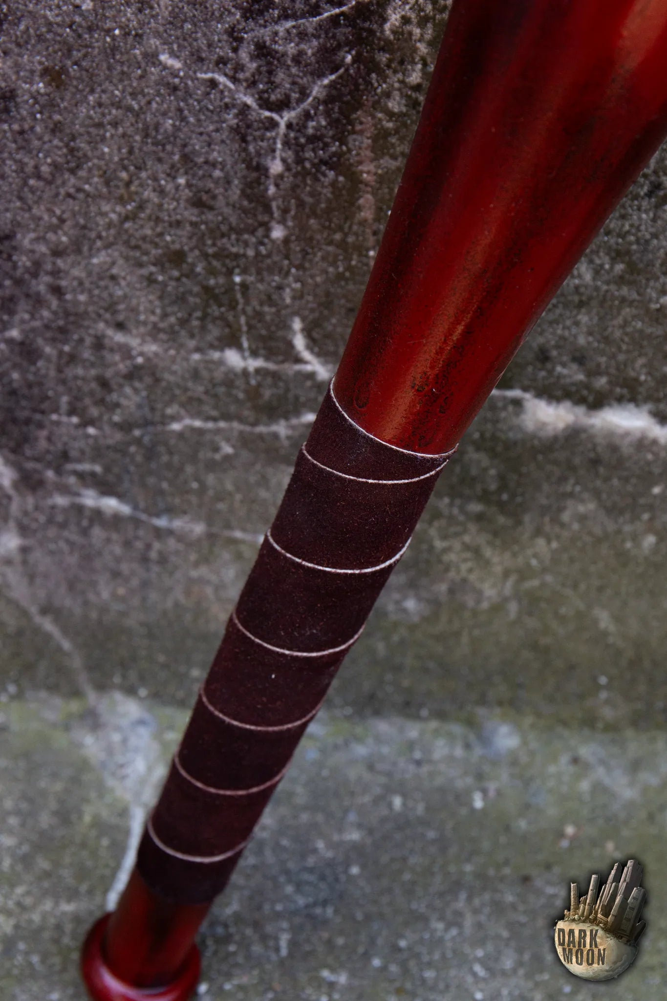 Close-up of a Barbed Wire Bat with a red wooden design and textured grip.