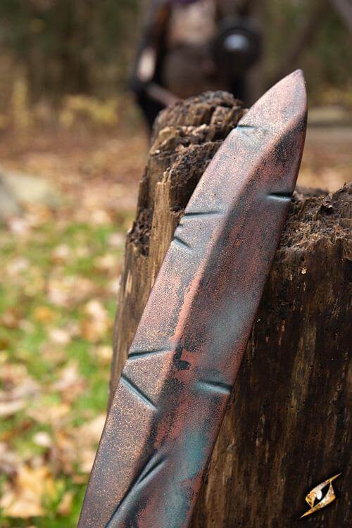 Battleworn Falcata resting against a wooden post, showcasing its realistic handmade detail.
