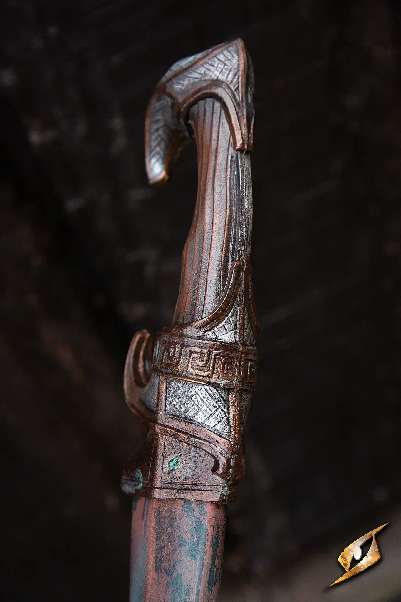 Close-up of the ornate hilt of the Battleworn Falcata, featuring intricate designs and a weathered finish.