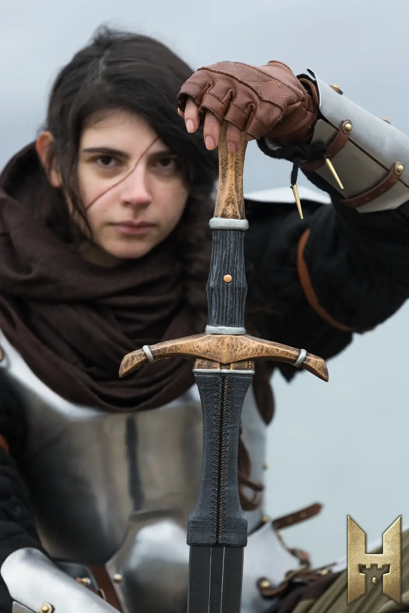 Bastard Sword held by a warrior in medieval armor, showcasing its intricate handle and blade design.