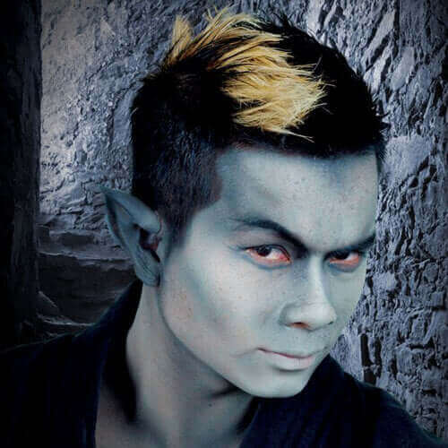 Close-up of a fantasy character with green skin and spiky hair, set against a stone wall background.