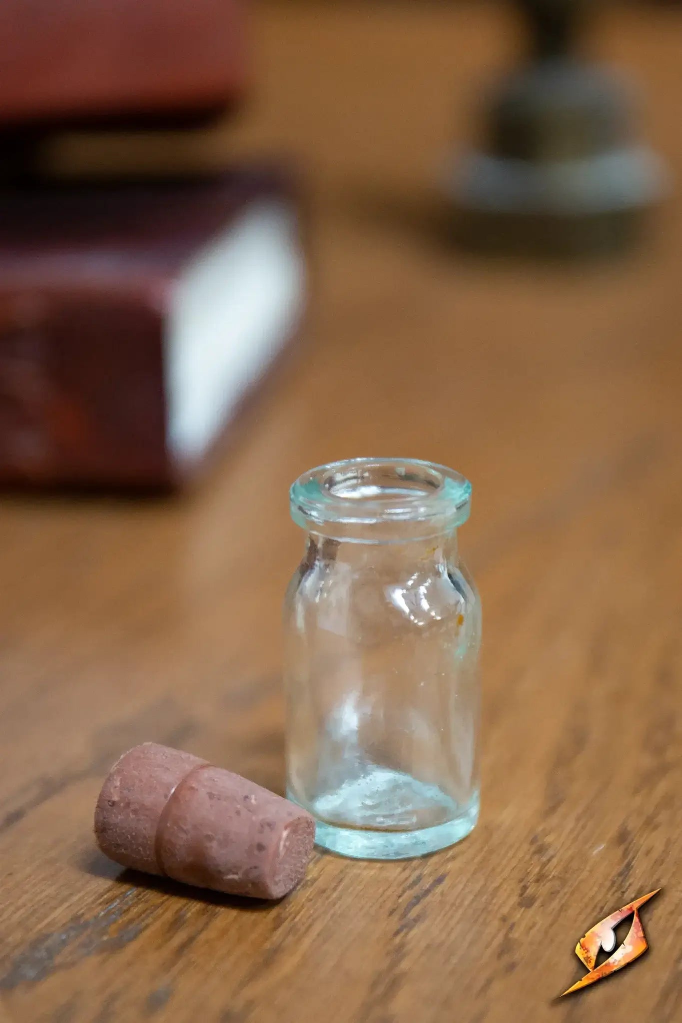 Small glass Potion Flask Small with cork on a wooden table, surrounded by old books and laboratory items.