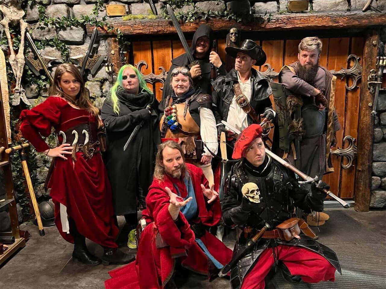 Group of people in fantasy costumes posing with swords and props in a medieval-themed setting.