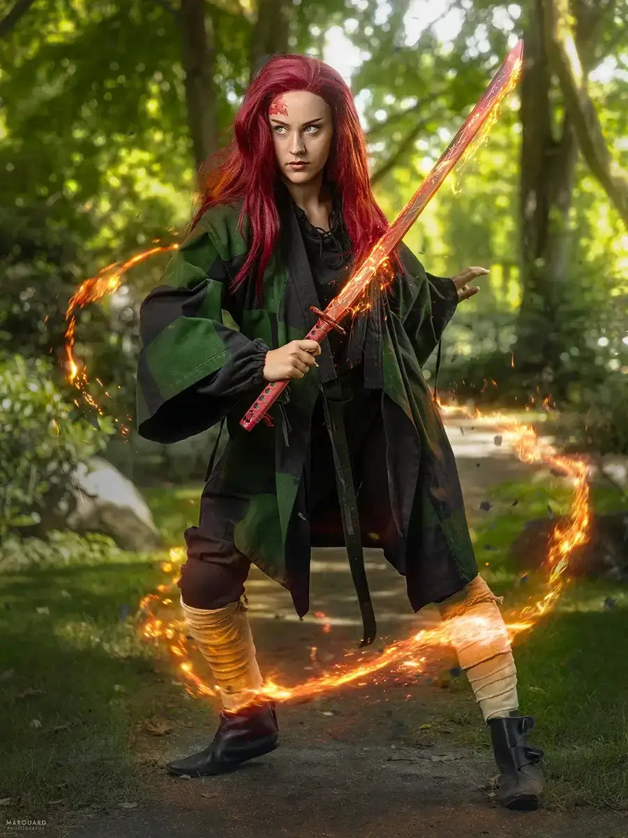 Warrior in vibrant costume wielding a red sword with fiery effects, set against a lush green background.