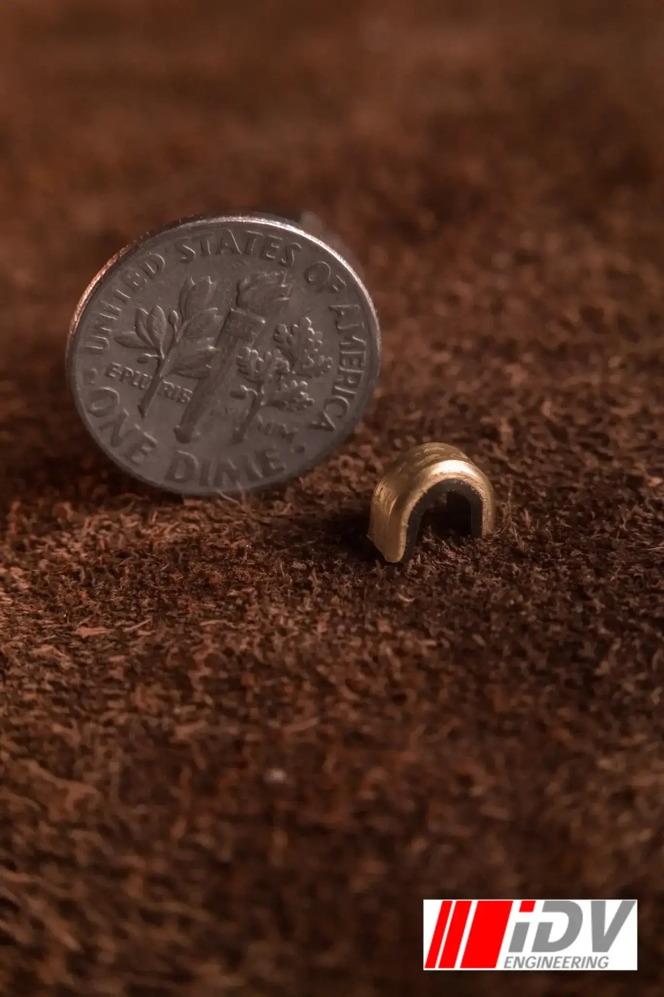 String Nock Marker size comparison with a dime on a brown textured background.