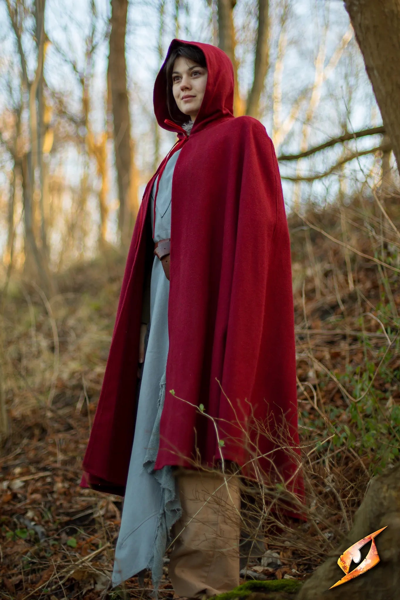 Person wearing a red Cape Wool in a forest setting, showcasing its deep hood and stylish design.
