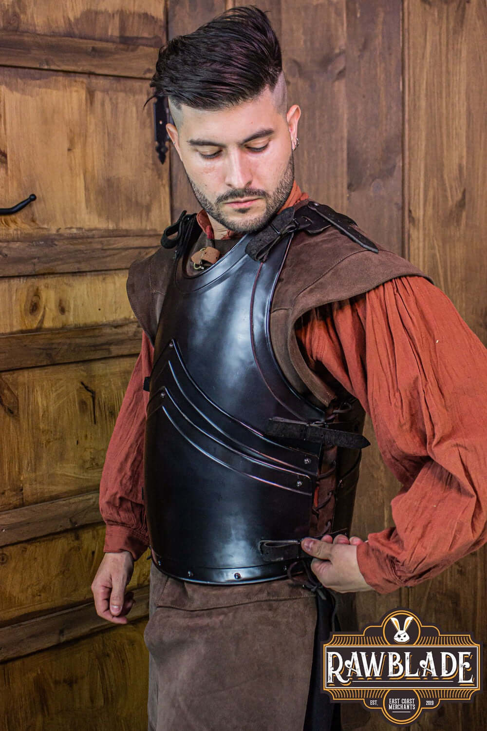 Alonso Cuirass showcasing a crafted iron breastplate with leather straps, modeled by a man in a rustic setting.