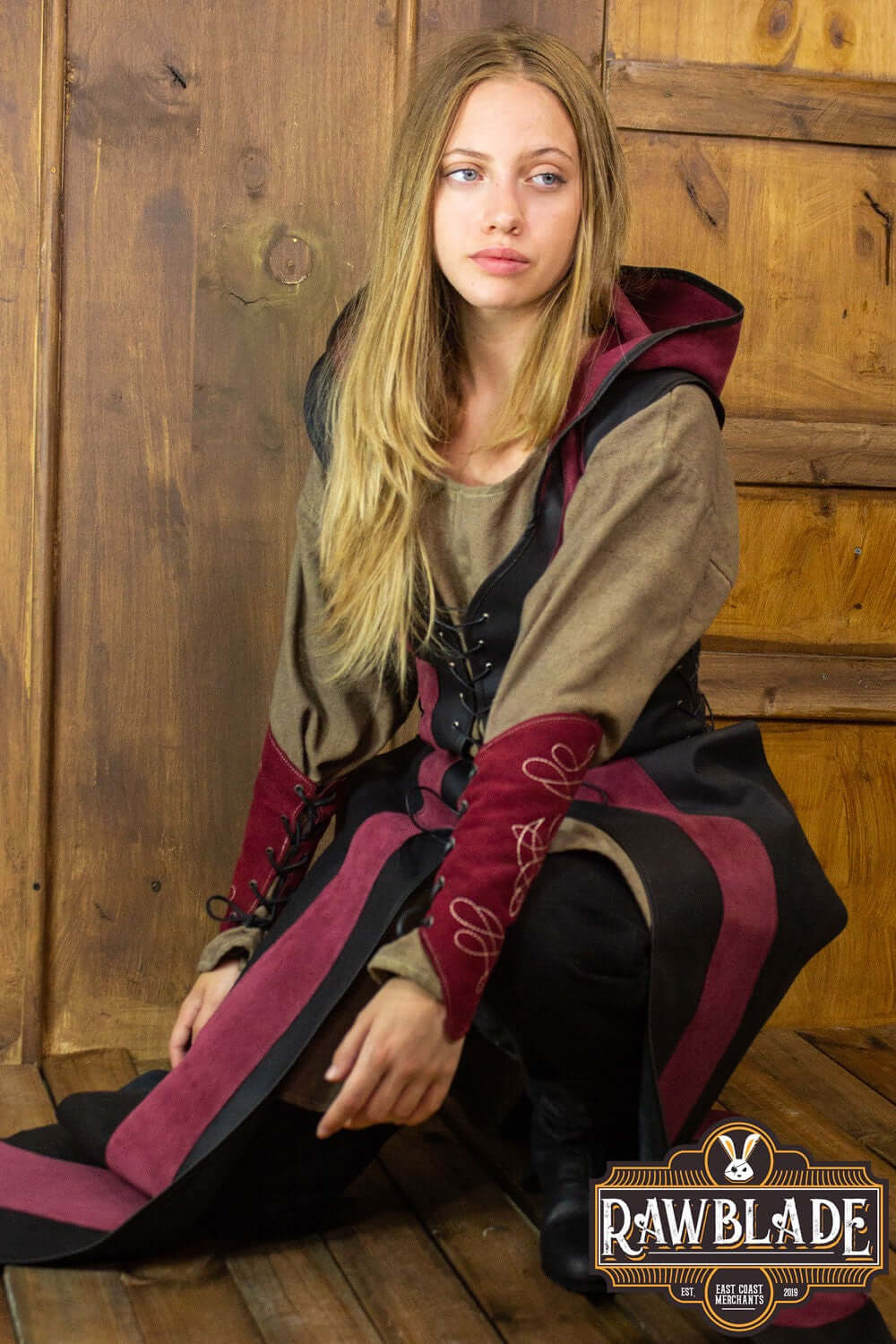 Arylith Archer Leather Tunic model wearing a fitted leather tunic with a wide hood, showcased in a rustic setting.