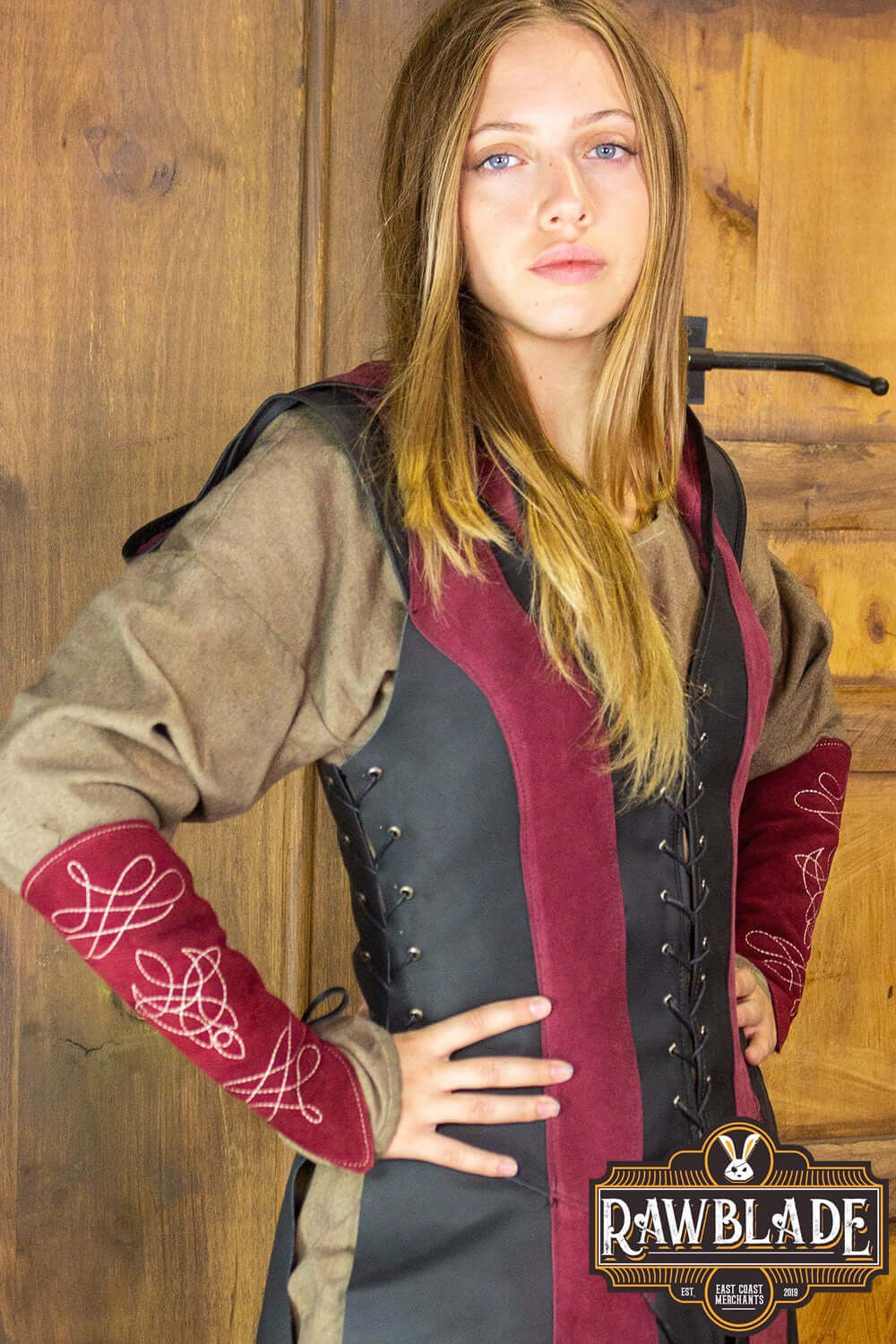 A young woman wearing the Arylith Archer Leather Tunic, featuring adjustable drawstrings and a wide hood.