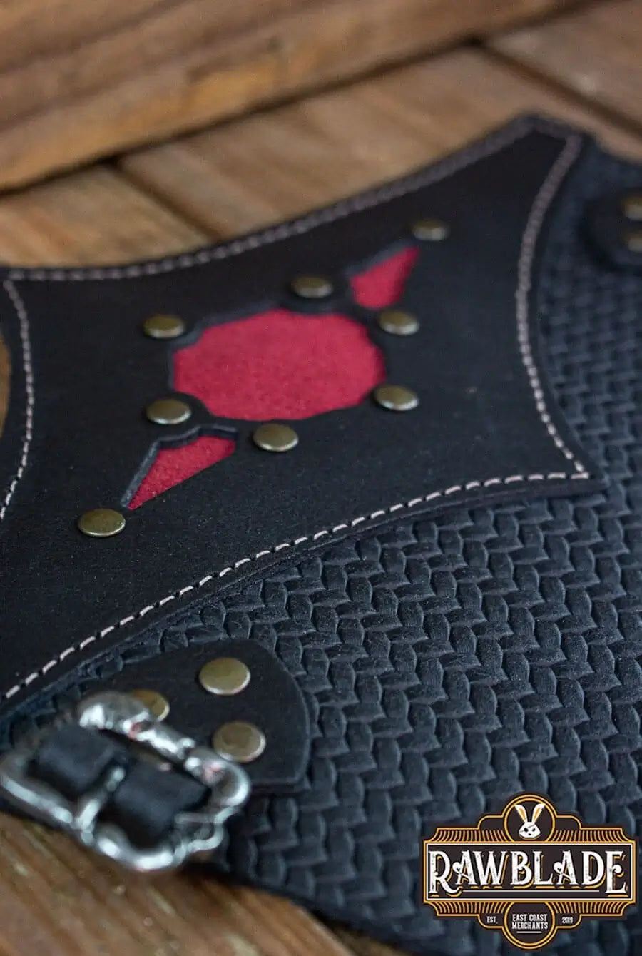 Close-up of Beljant Bracer with red diamond and decorative studs on a textured leather background.