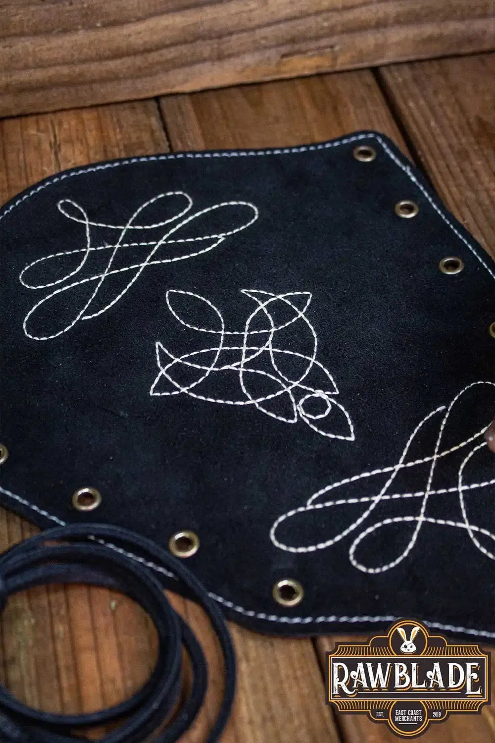 Vryla Premium Bracers in black leather with decorative stitching on wooden background
