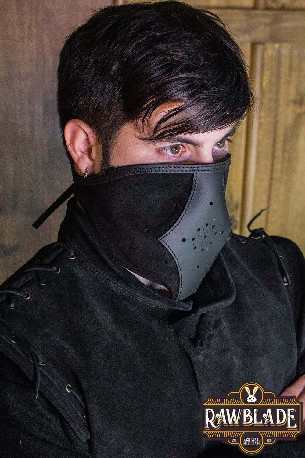 Man wearing the Akku Splitleather Hood with mask, featuring leather reinforcements and metal ornaments.