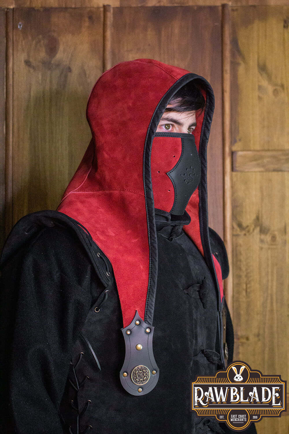 Akku Splitleather Hood worn by a character with a red and black design, featuring leather reinforcements and metal ornaments.