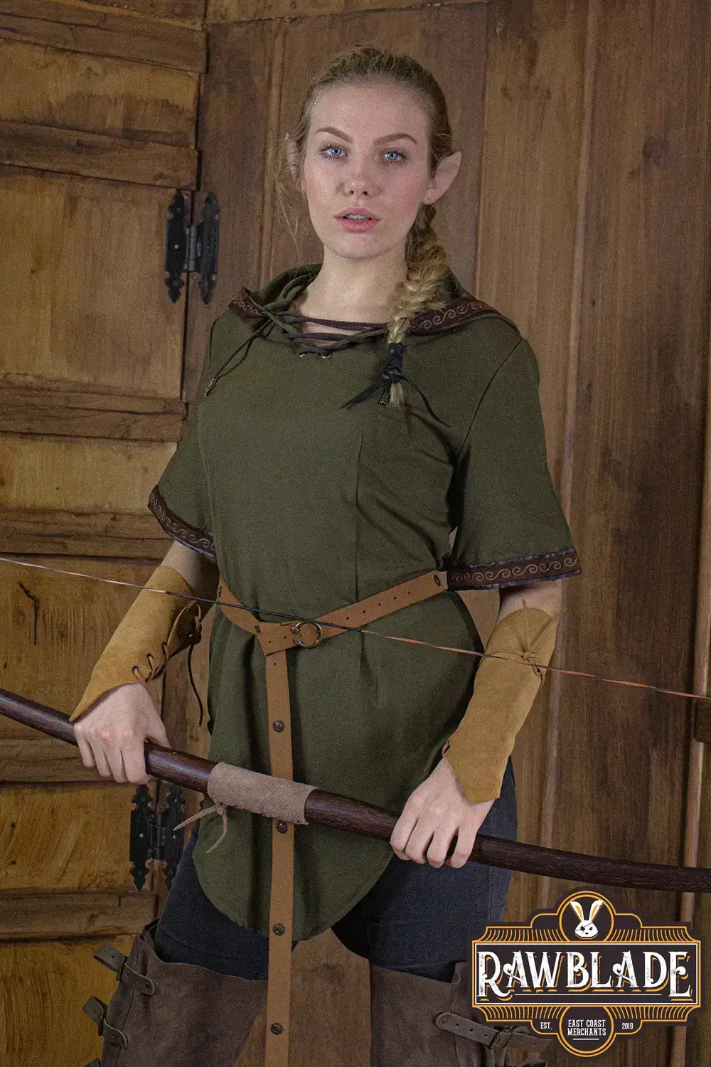 A model wearing the Briannan Ranger Tunic from Rawblade, featuring a wide hood and leather-trimmed short sleeves.