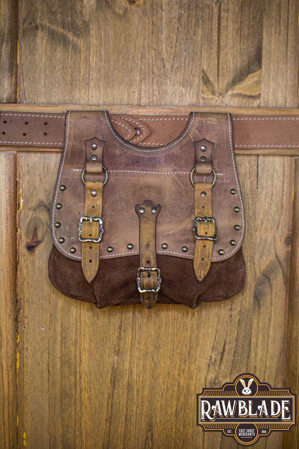 Agor Belt Bag displayed on a wooden background, crafted from two types of leather with buckles and studs.