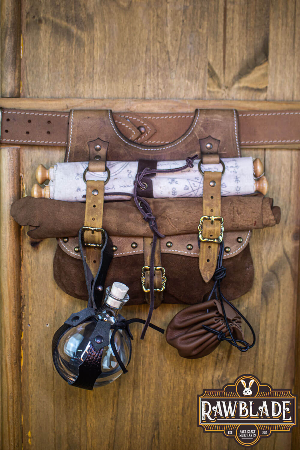 Agor Belt Bag displayed on a wooden background, made from brown leather with detailed buckles.