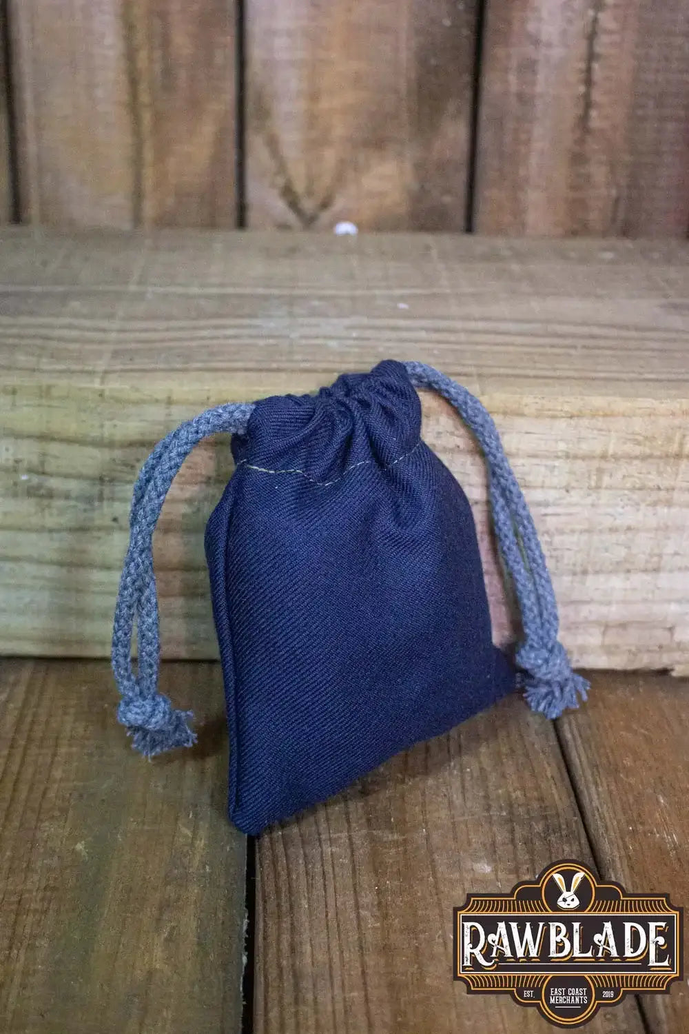 Timber Pouch Premium in navy blue cotton fabric with drawstring closure, set against a wooden background.