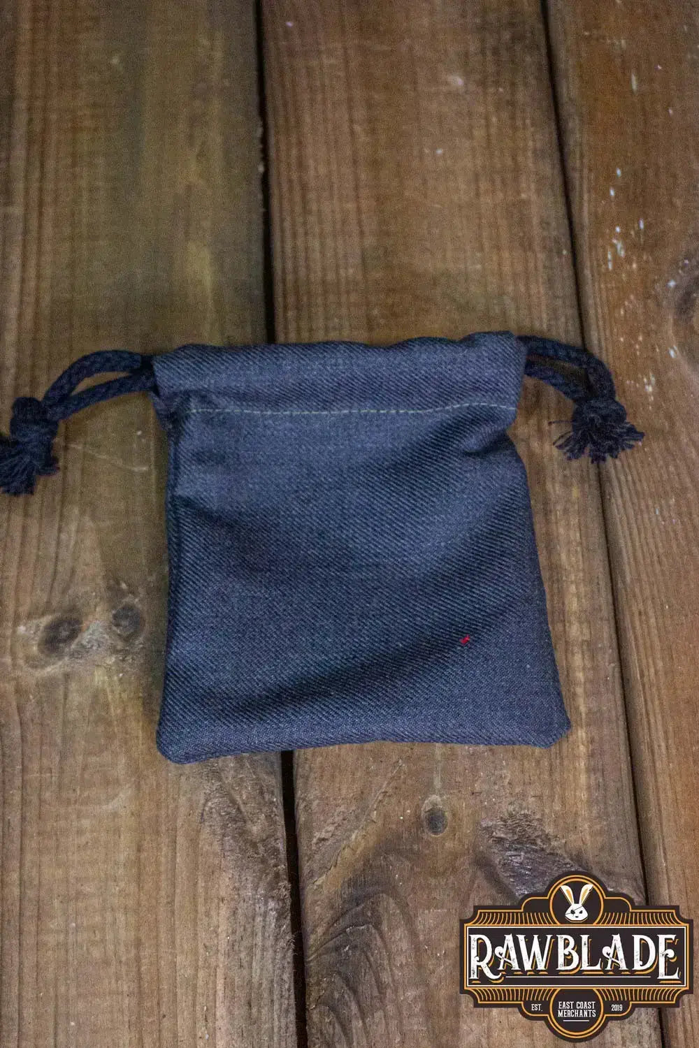 Timber Pouch Premium in dark fabric with drawstring on a wooden background.