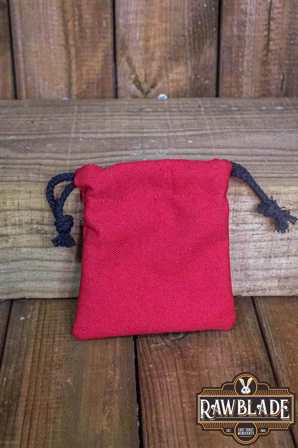Timber Pouch Premium in vibrant red cotton fabric with a drawstring closure on a wooden surface.
