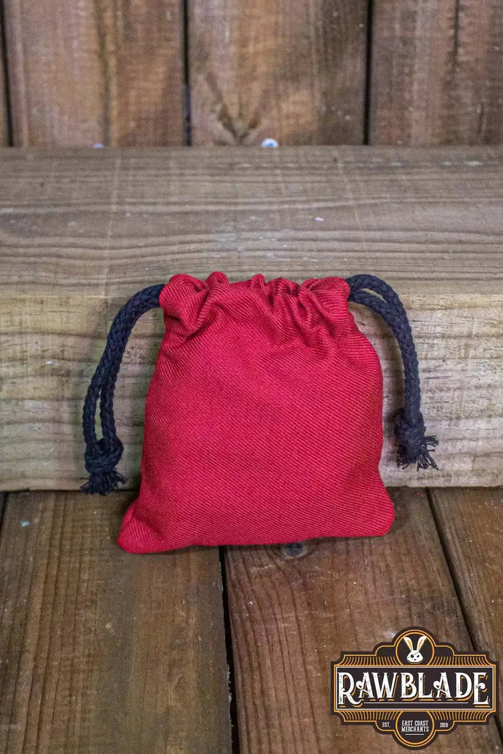 Timber Pouch Premium in red color, made of thick cotton with drawstring closure on wooden background.
