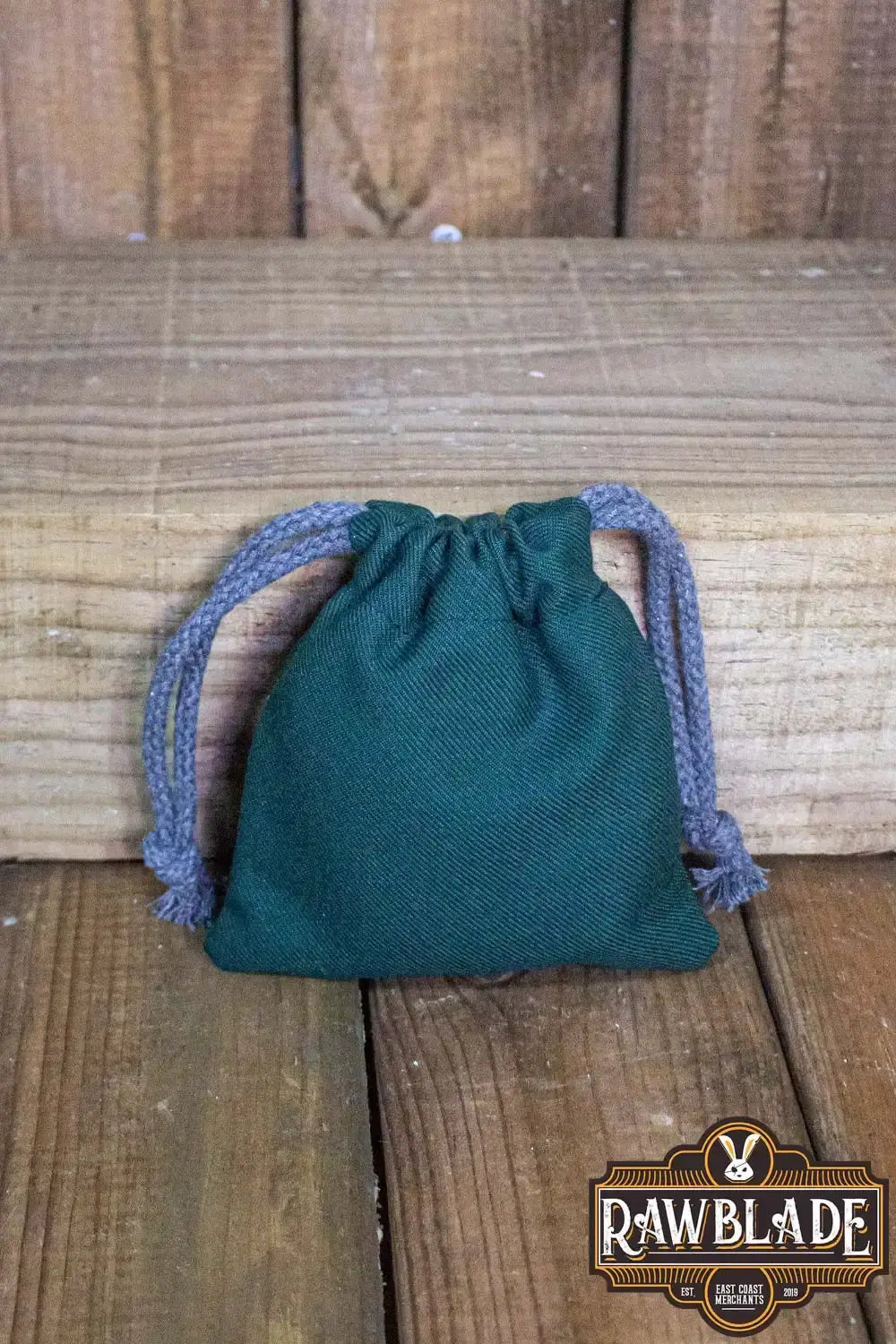 Timber Pouch Premium in dark green cotton fabric with gray drawstrings, placed on wooden surface.