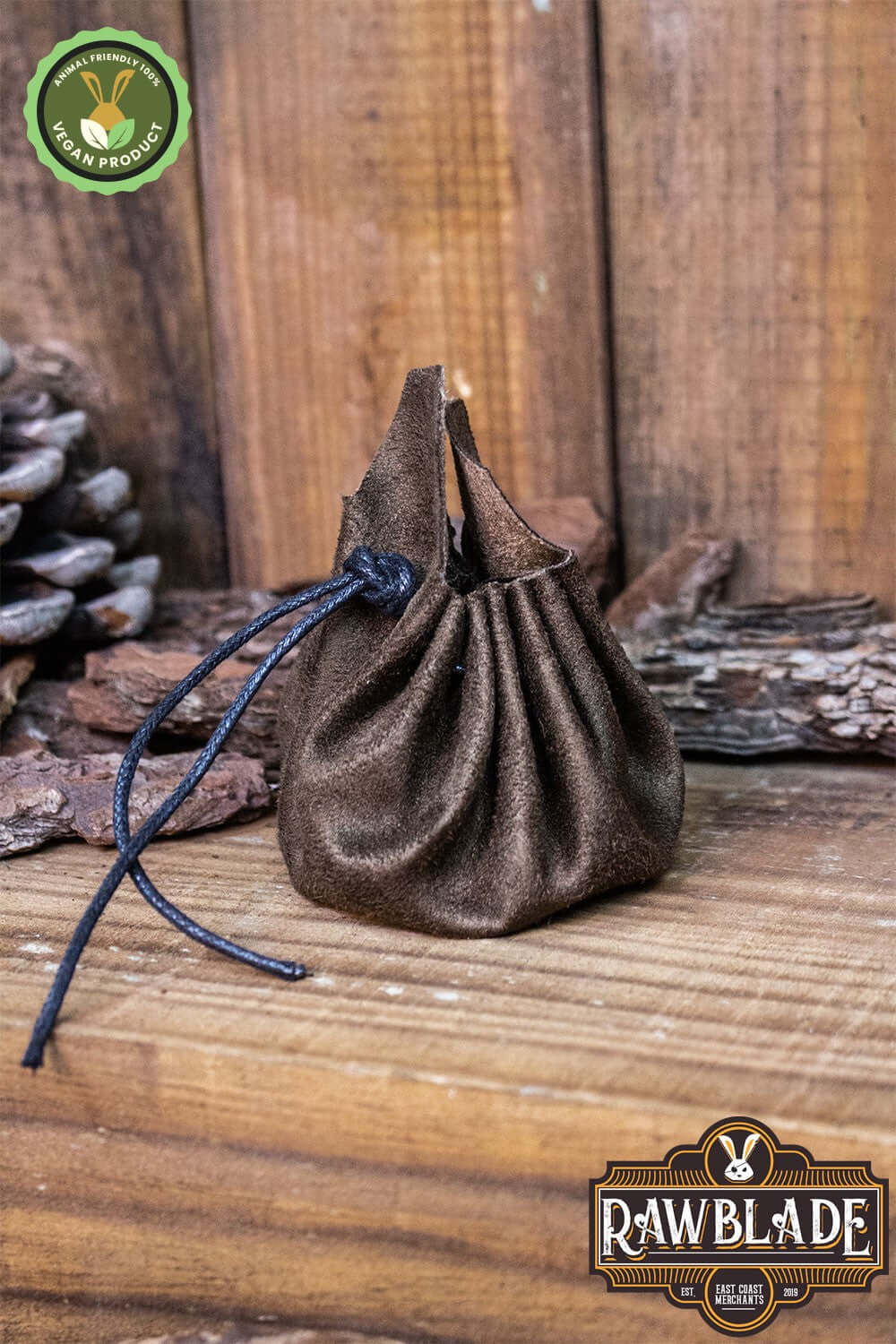 Adventurer's Coin Bag, Leather Free sits on a wooden surface, showcasing its circular shape and vegan suede material.