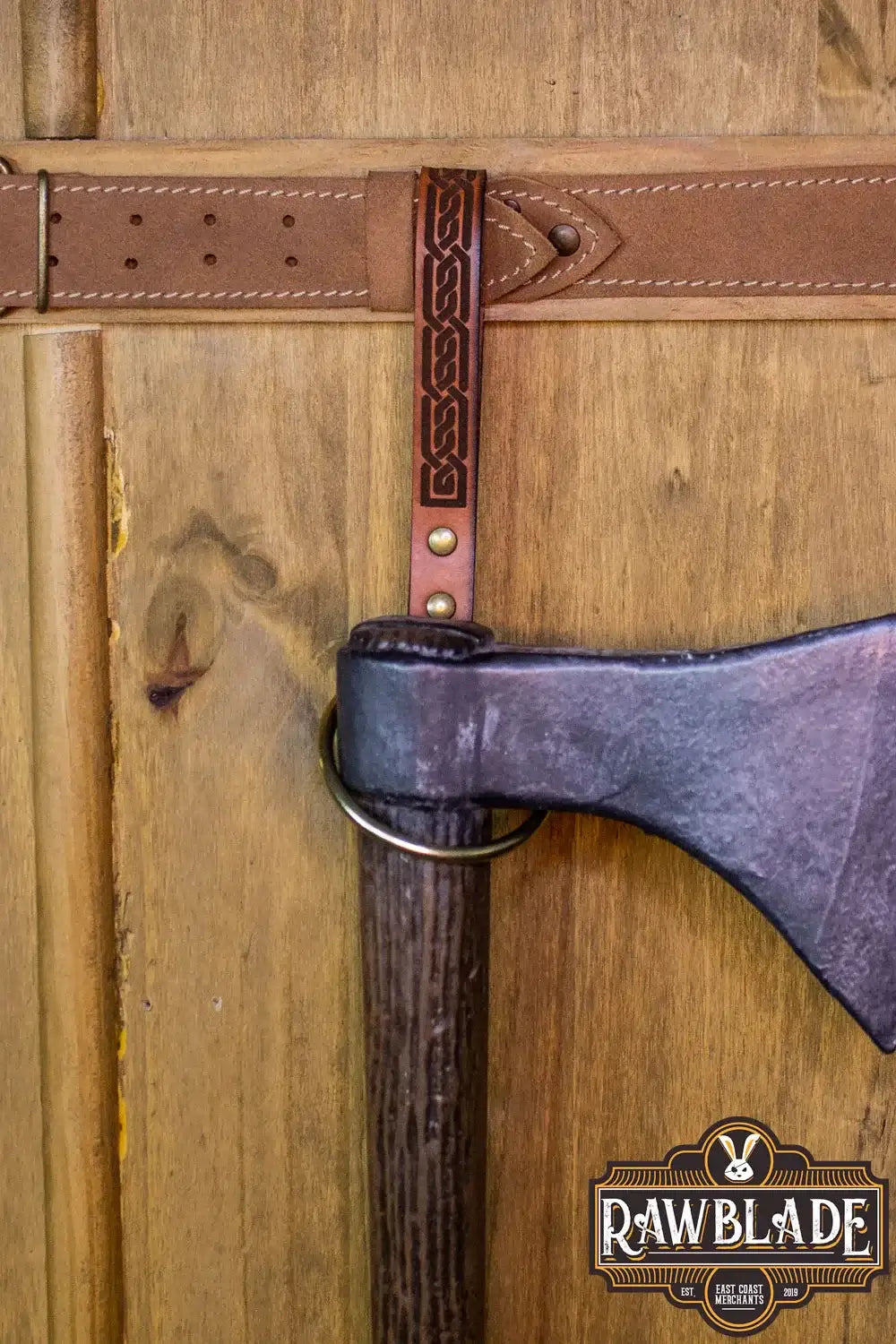 Runar Ring Holder displaying ornate leather design and metal rivet on a wooden background.