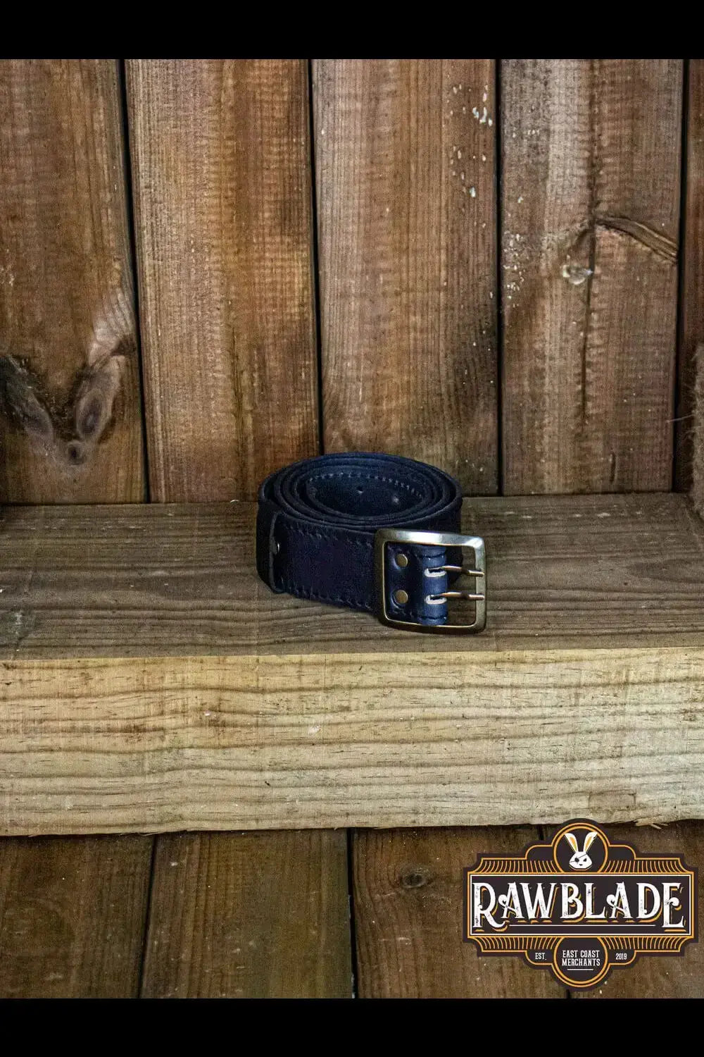 Adventurer Belt made of cowhide leather with a medieval-style buckle, resting on a wooden surface.